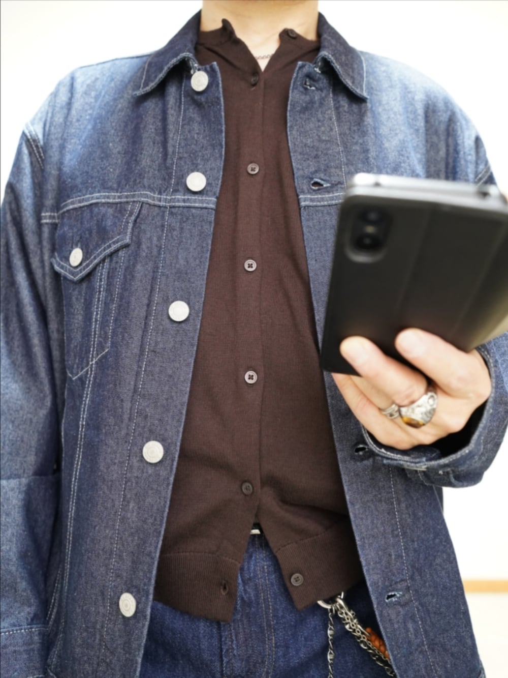 ブラック系のドレスシューズ、ブルー系のデニムパンツ、ブラウン系のカーディガン/ボレロを着用したメンズの春コーディネートの3枚目の写真