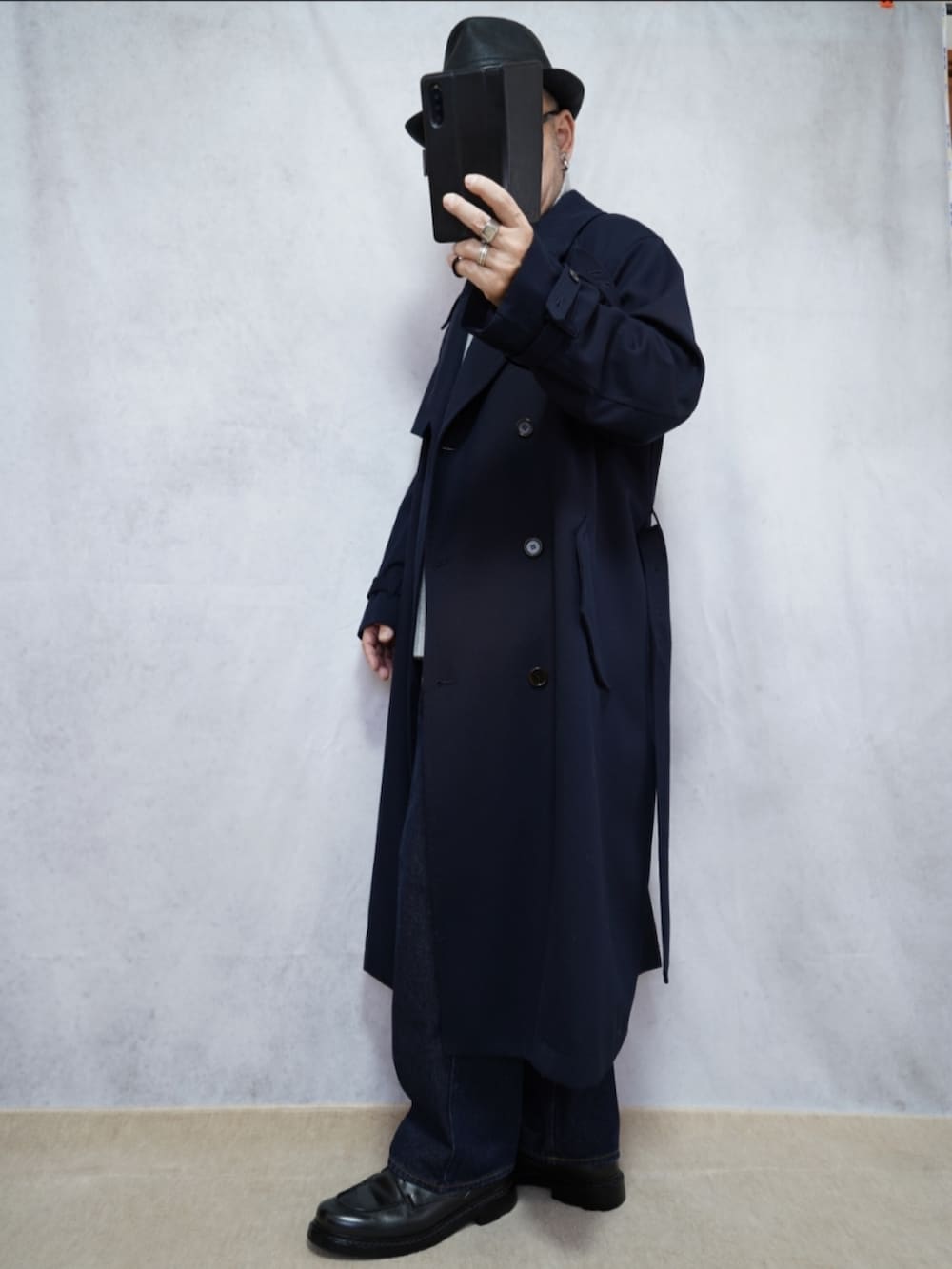 ブラック系のシューズ、ブルー系のデニムパンツ、ブルー系のトレンチコートを着用したメンズの冬コーディネートの2枚目の写真