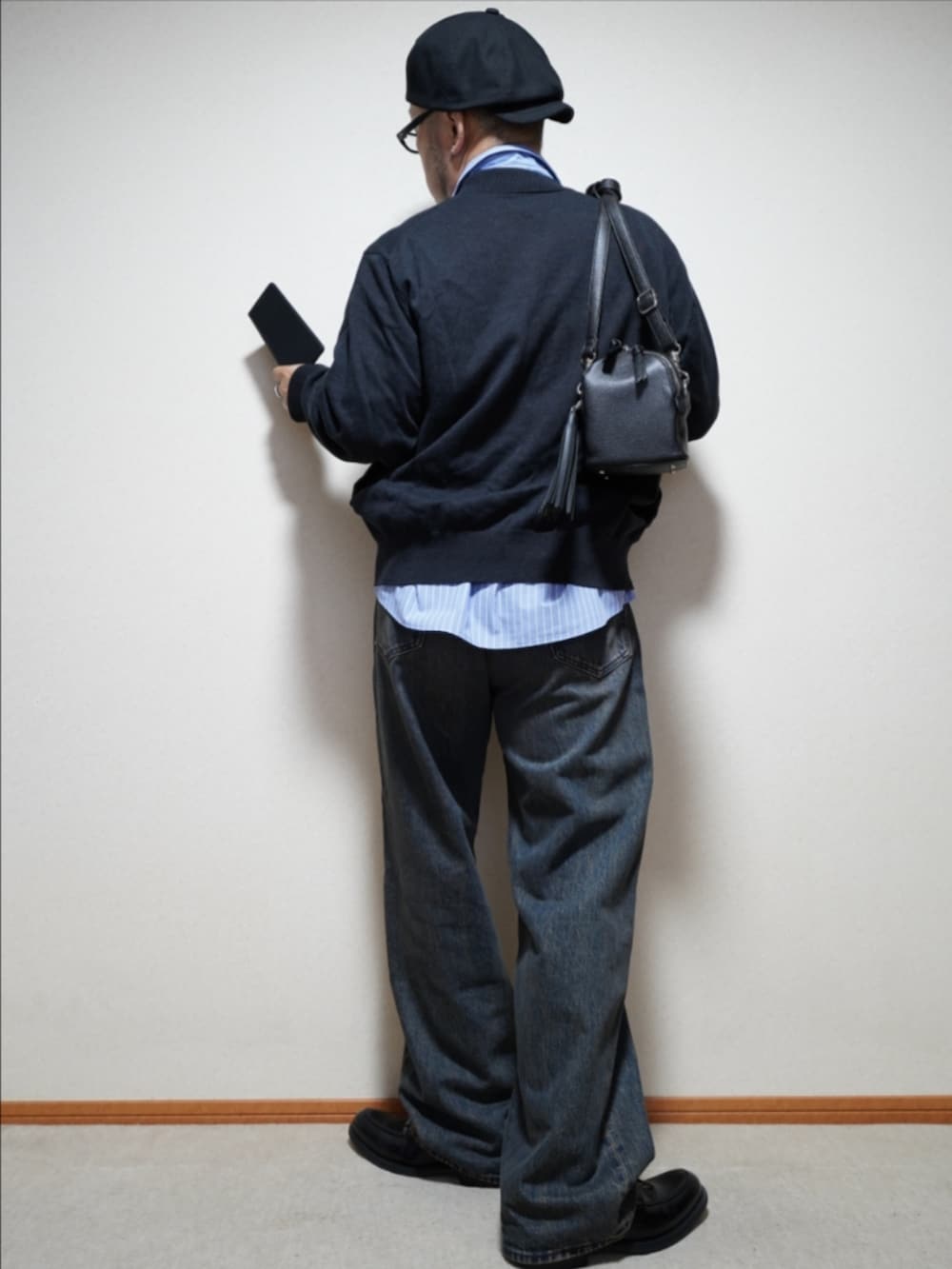 ブラック系のシューズ、ブルー系のデニムパンツ、ブラック系のショルダーバッグを着用したメンズの秋コーディネートの4枚目の写真