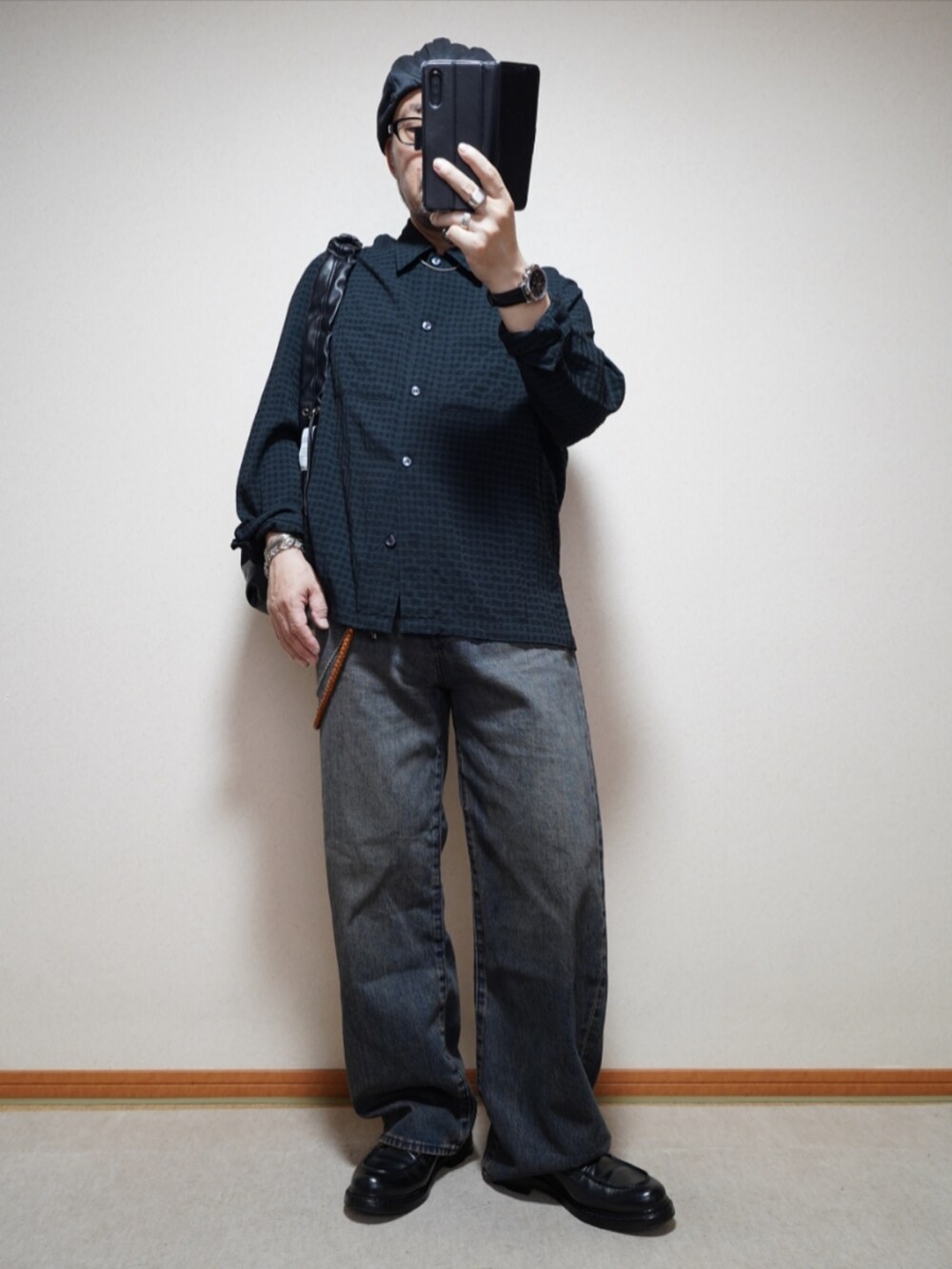 ブラック系のシューズ、ブルー系のデニムパンツ、ブラック系のショルダーバッグを着用したメンズの春コーディネートの2枚目の写真