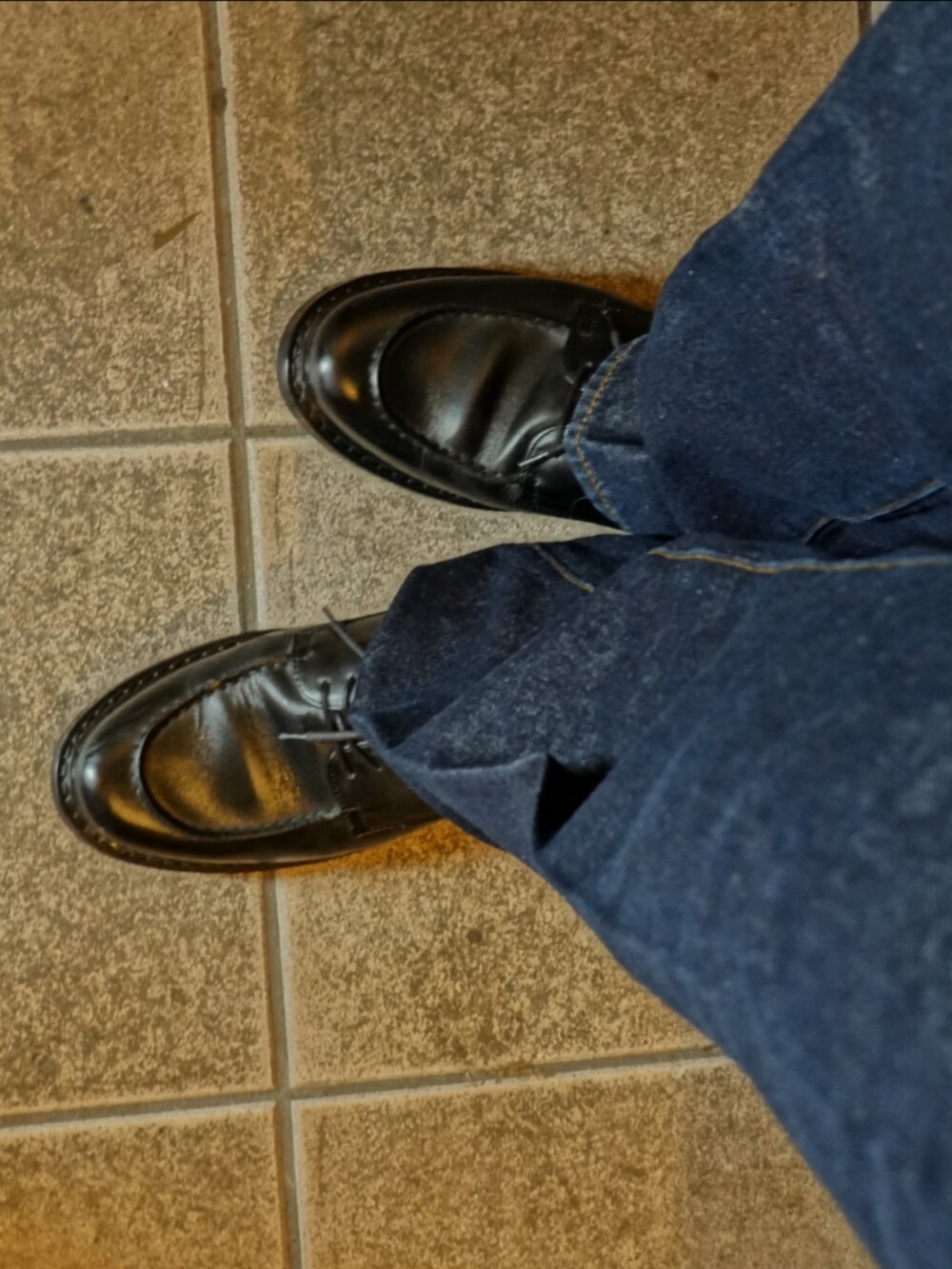 ブラック系のシューズ、ブルー系のデニムパンツ、ホワイト系のニット/セーターを着用したメンズの春コーディネートの3枚目の写真