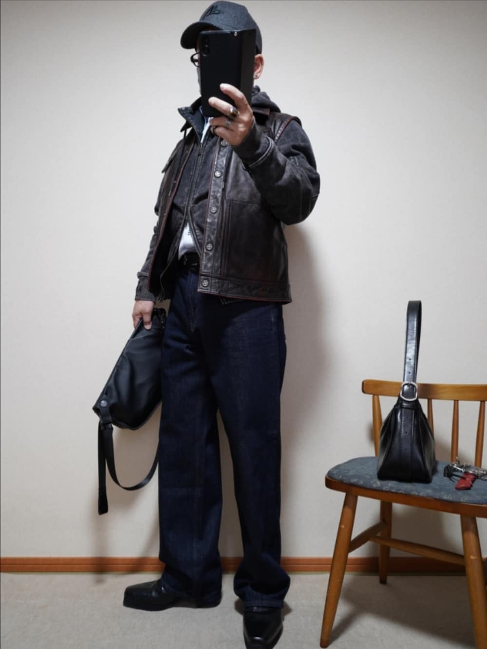 ブラック系のブーツ、ブルー系のデニムパンツ、ブラック系のパーカーを着用したメンズの春コーディネートの2枚目の写真