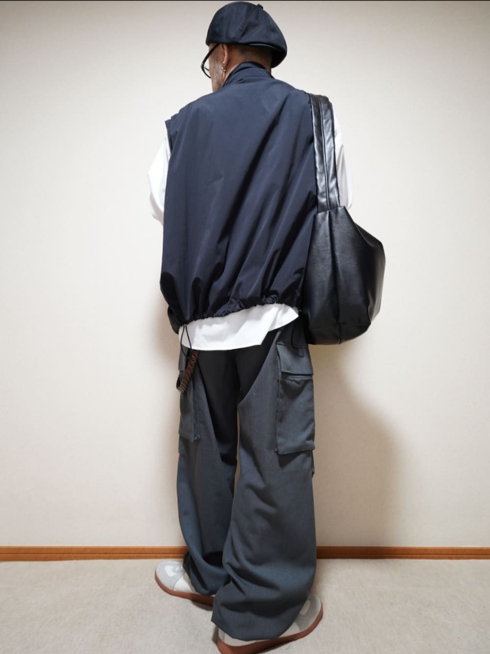 ホワイト系のスニーカー、グレー系のカーゴパンツ、ブラック系のショルダーバッグを着用したメンズの秋コーディネートの3枚目の写真