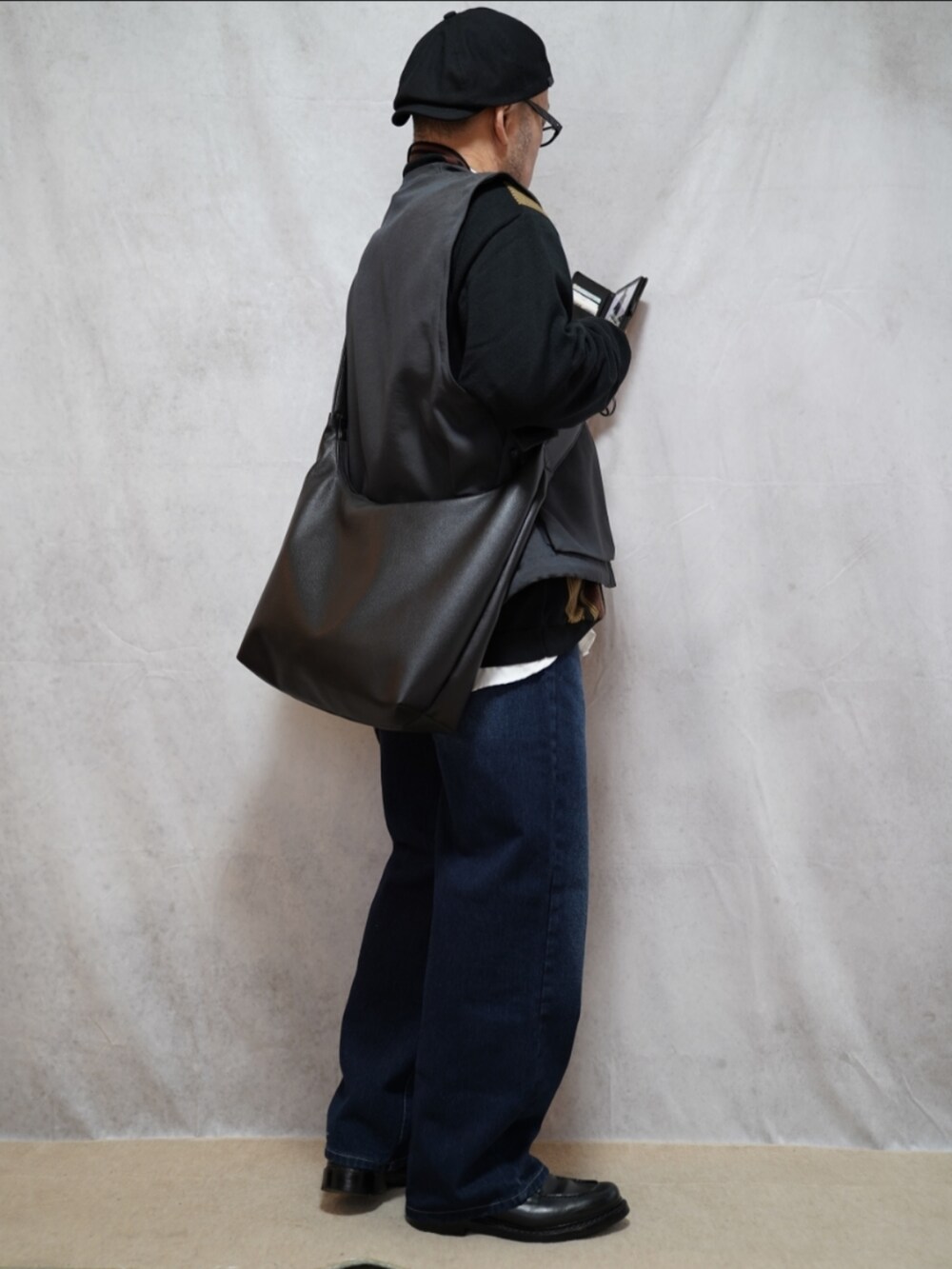 ブラック系のシューズ、ブルー系のデニムパンツ、ブラック系のカーディガン/ボレロを着用したメンズの春コーディネートの4枚目の写真