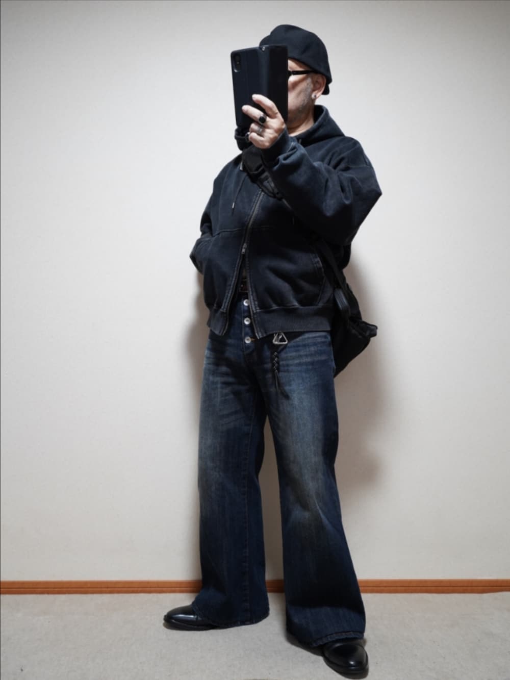 ブラック系のドレスシューズ、ブルー系のデニムパンツ、ブラック系のパーカーを着用したメンズの冬コーディネートの2枚目の写真