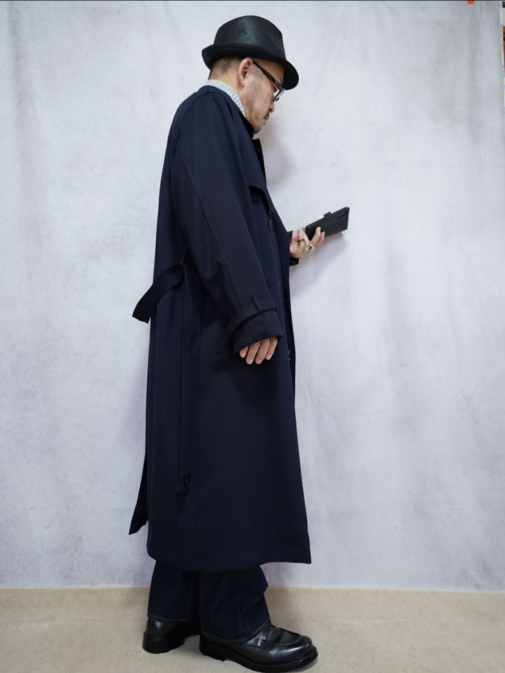 ブラック系のシューズ、ブルー系のデニムパンツ、ブルー系のトレンチコートを着用したメンズの冬コーディネートの4枚目の写真