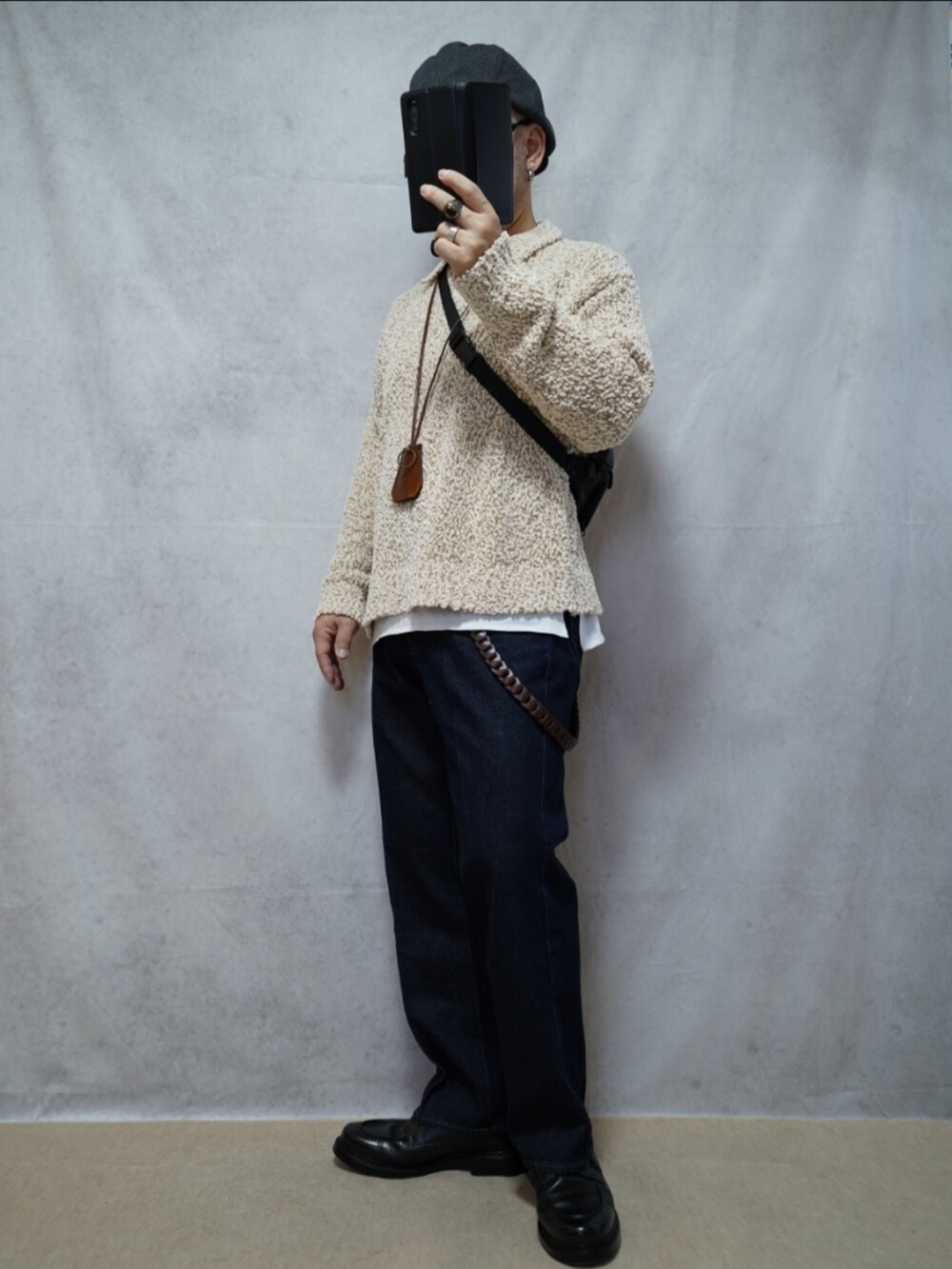 ブラック系のシューズ、ブルー系のデニムパンツ、ホワイト系のニット/セーターを着用したメンズの春コーディネートの2枚目の写真