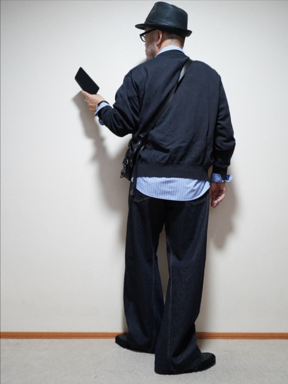 ブラック系のスニーカー、ブルー系のデニムパンツ、グレー系のシャツ/ブラウスを着用したメンズの秋コーディネートの4枚目の写真