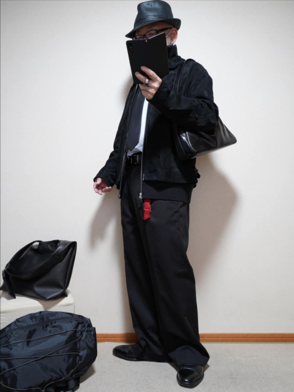 ブラック系のドレスシューズ、ブラック系のスラックス、ブラック系のショルダーバッグを着用したメンズの春コーディネートの2枚目の写真
