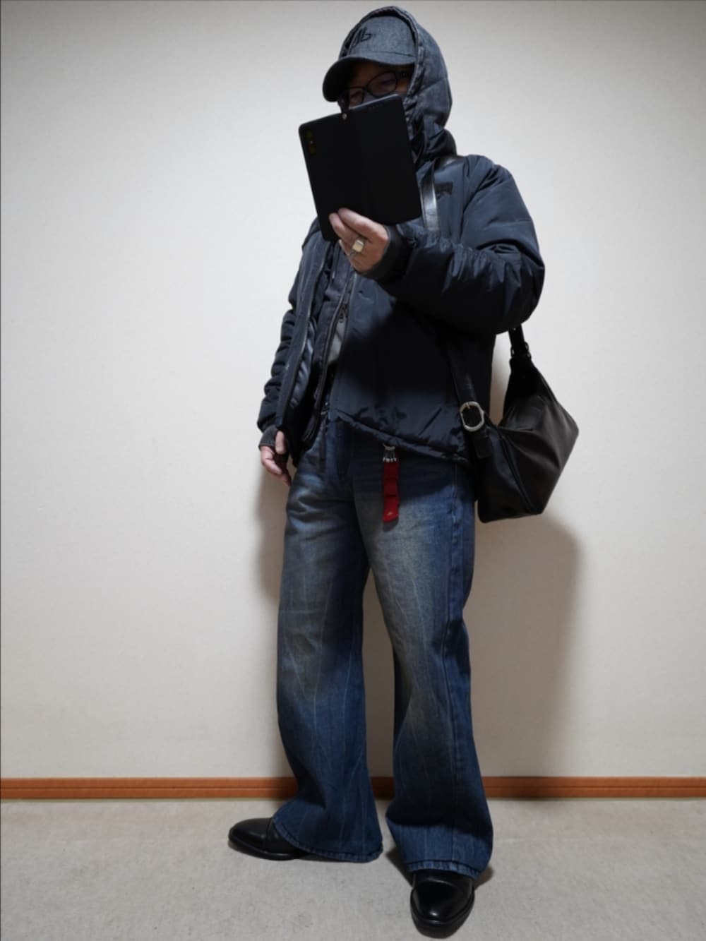 ブラック系のドレスシューズ、ブルー系のデニムパンツ、ブラック系のショルダーバッグを着用したメンズの冬コーディネートの2枚目の写真