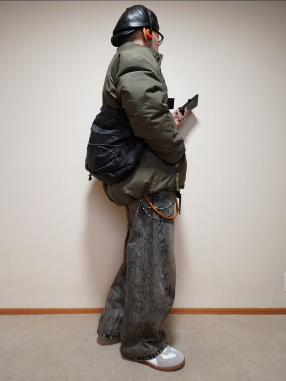 ホワイト系のスニーカー、ブルー系のデニムパンツ、グリーン系のミリタリージャケットを着用したメンズの冬コーディネートの4枚目の写真