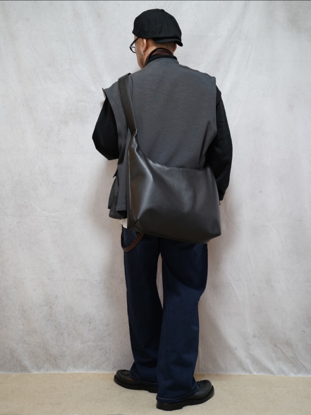 ブラック系のシューズ、ブルー系のデニムパンツ、ブラック系のカーディガン/ボレロを着用したメンズの春コーディネートの3枚目の写真