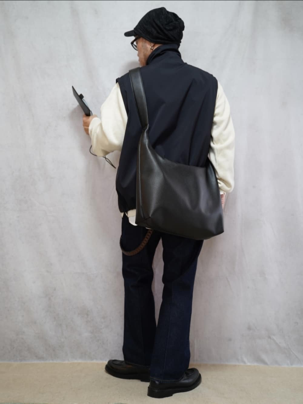 ブラック系のシューズ、ブルー系のデニムパンツ、ホワイト系のニット/セーターを着用したメンズの春コーディネートの3枚目の写真