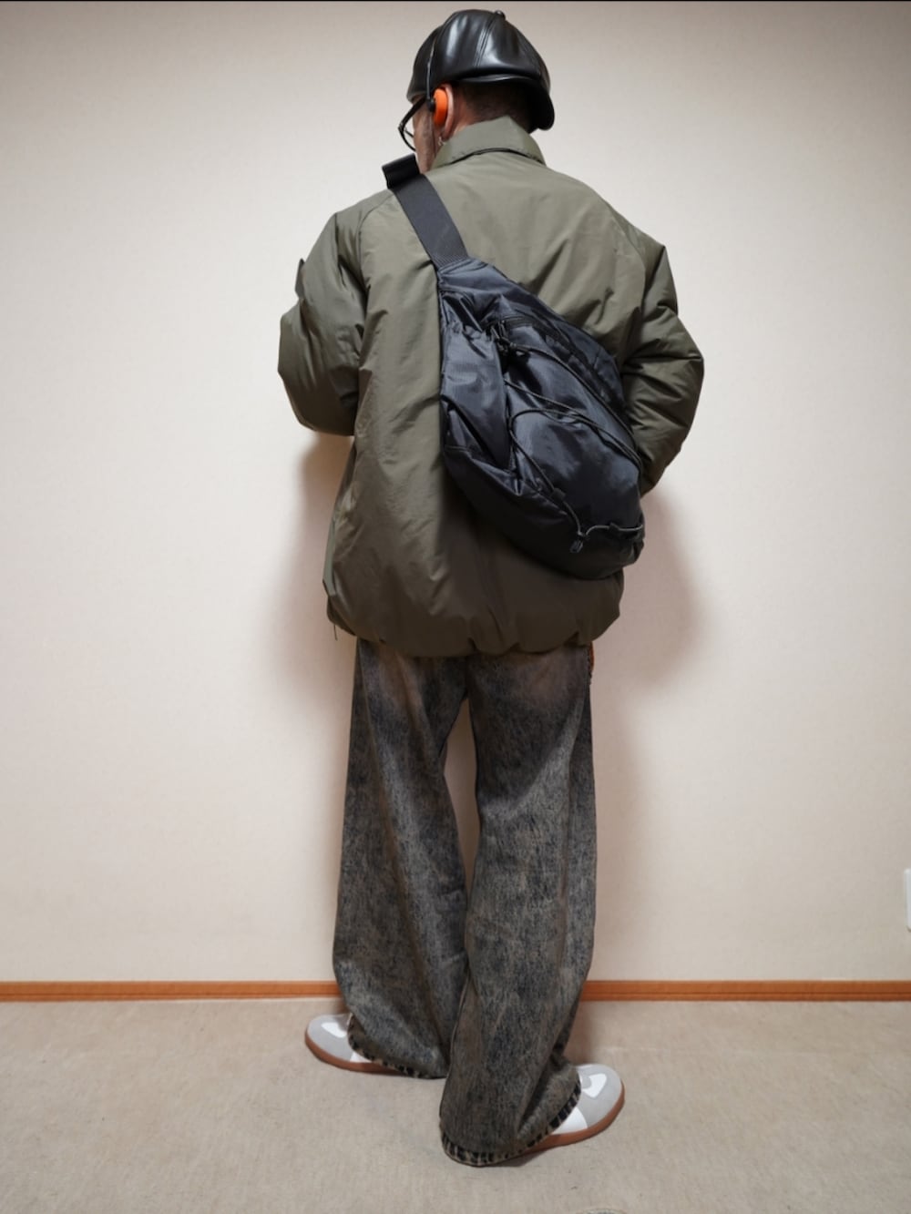 ホワイト系のスニーカー、ブルー系のデニムパンツ、グリーン系のミリタリージャケットを着用したメンズの冬コーディネートの3枚目の写真