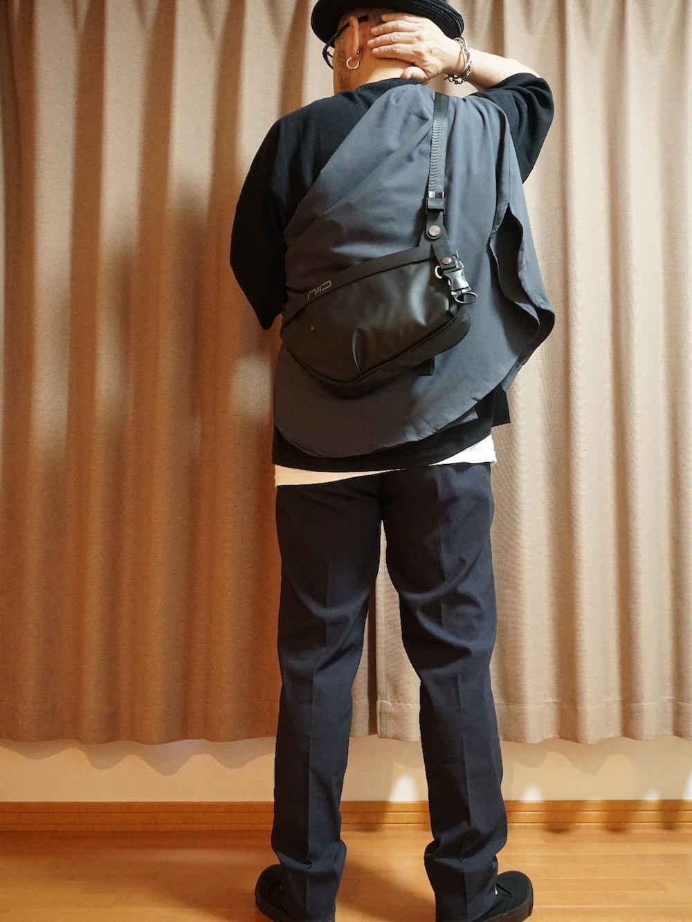 ブラック系のスリッポン、ブラック系のニット/セーター、ブラック系のボディバッグ/ウエストポーチを着用したメンズの夏コーディネートの2枚目の写真