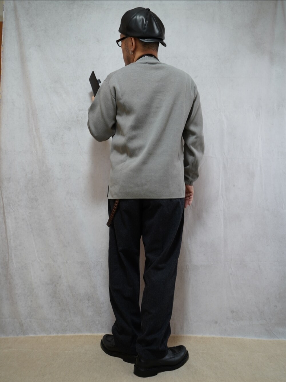 グレー系のパンツ、ブラック系のショルダーバッグ、グレー系のニット/セーターを着用したメンズの春コーディネートの3枚目の写真