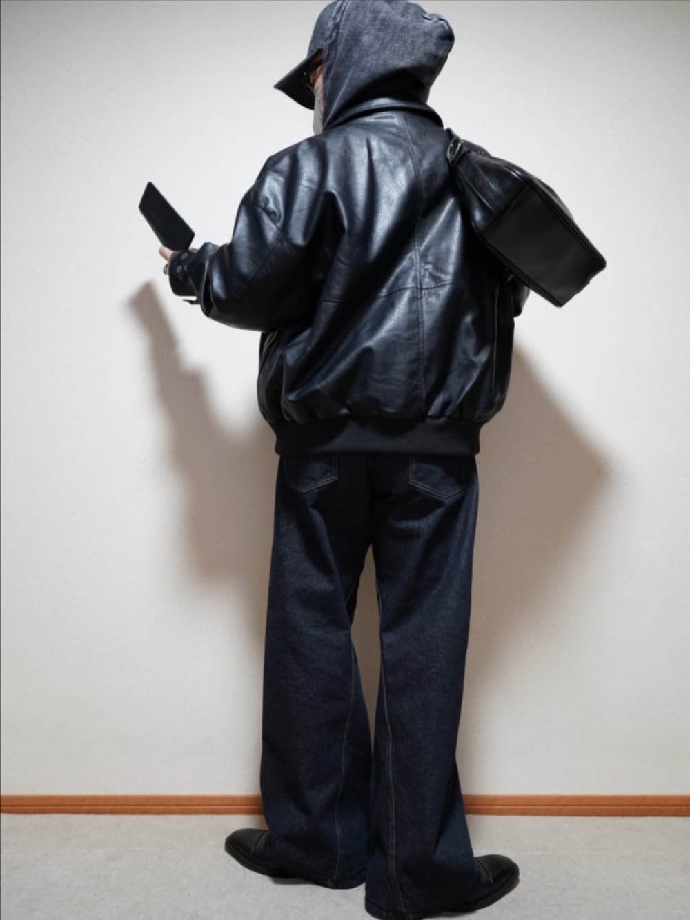 ブラック系のドレスシューズ、ブルー系のデニムパンツ、ブラック系のショルダーバッグを着用したメンズの冬コーディネートの4枚目の写真