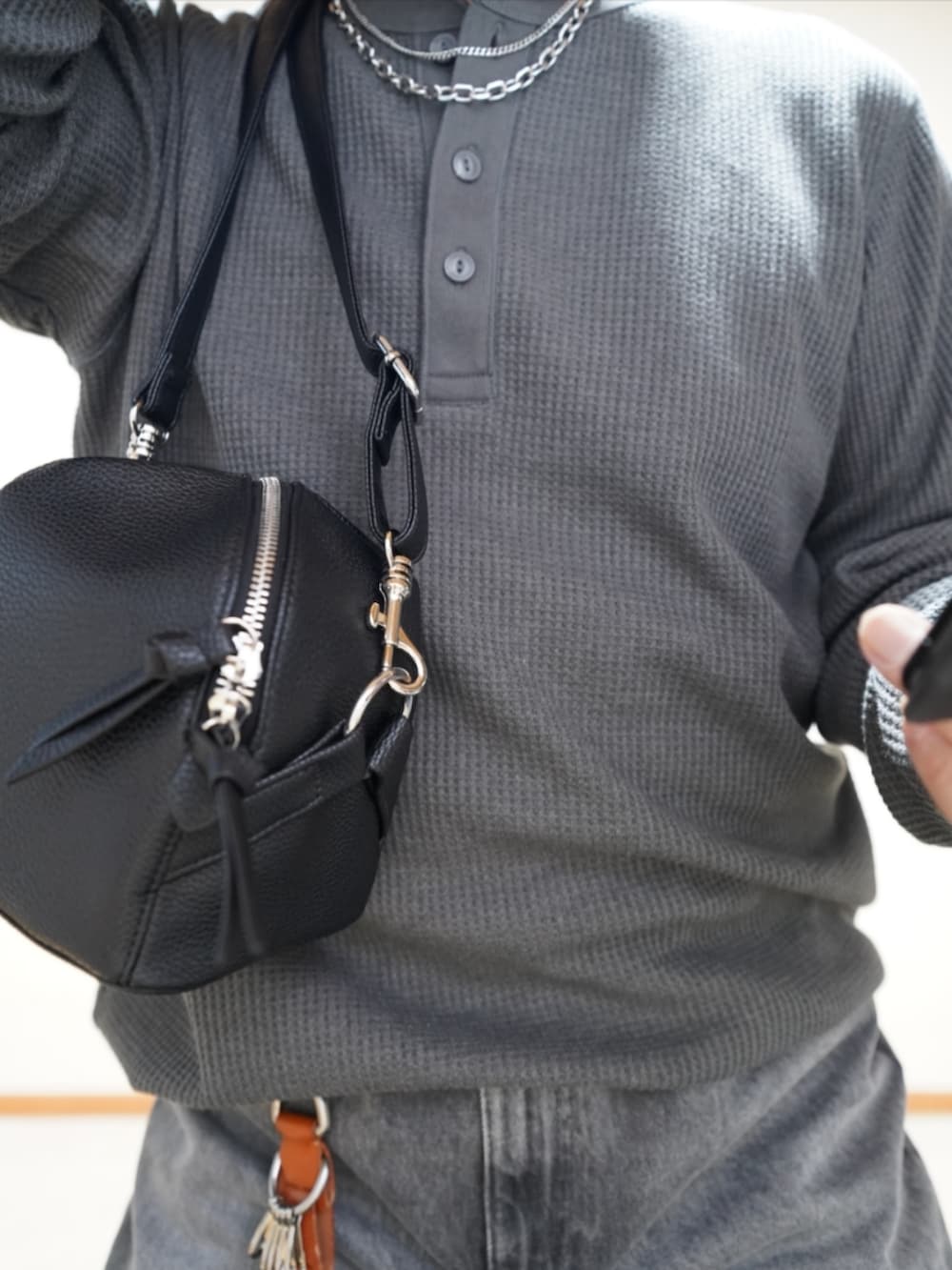 ブラック系のシューズ、グレー系のデニムパンツ、ブラック系のショルダーバッグを着用したメンズの夏コーディネートの4枚目の写真