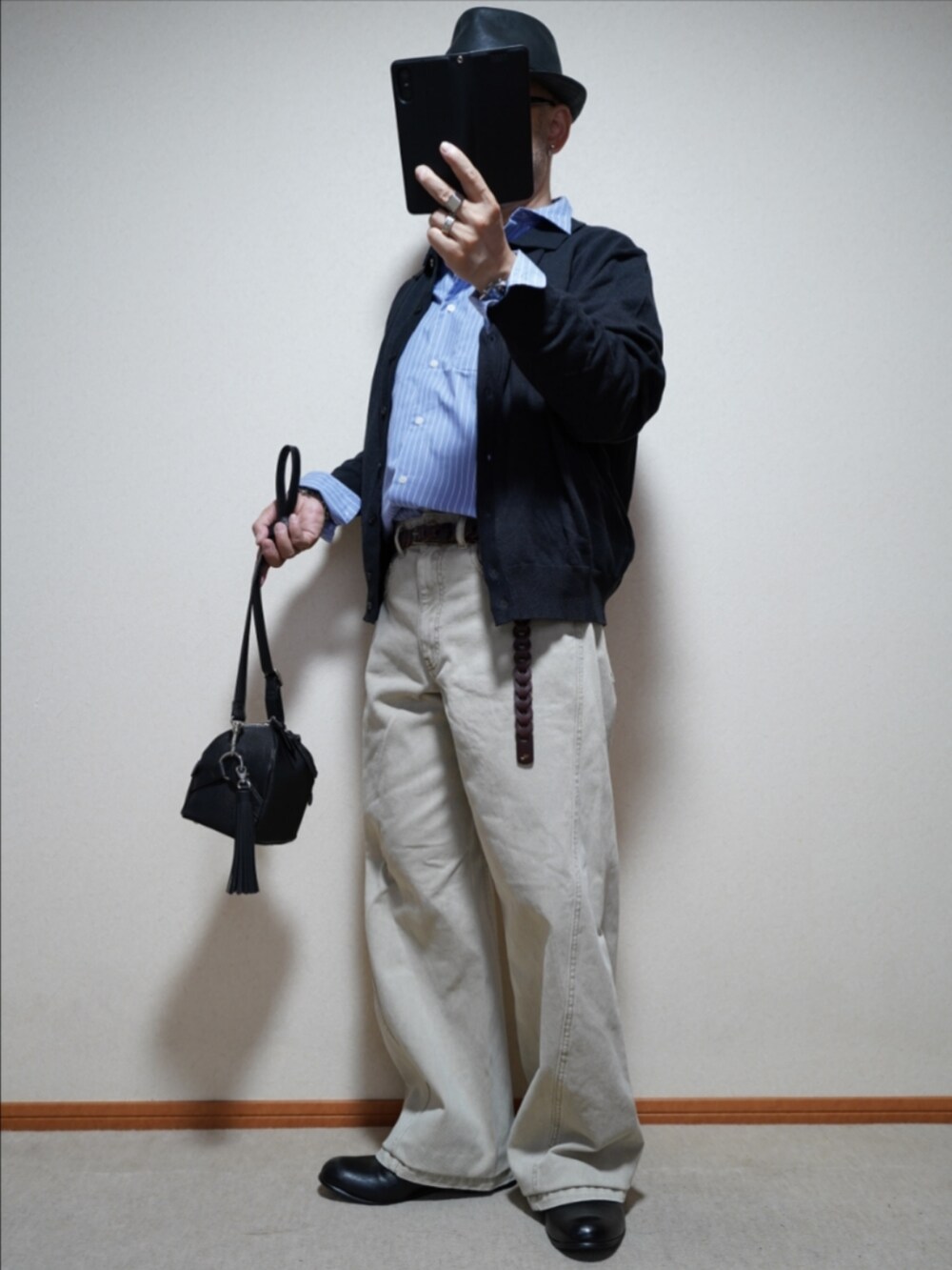 ブラック系のスリッポン、ベージュ系のデニムパンツ、ブラック系のショルダーバッグを着用したメンズの秋コーディネートの2枚目の写真