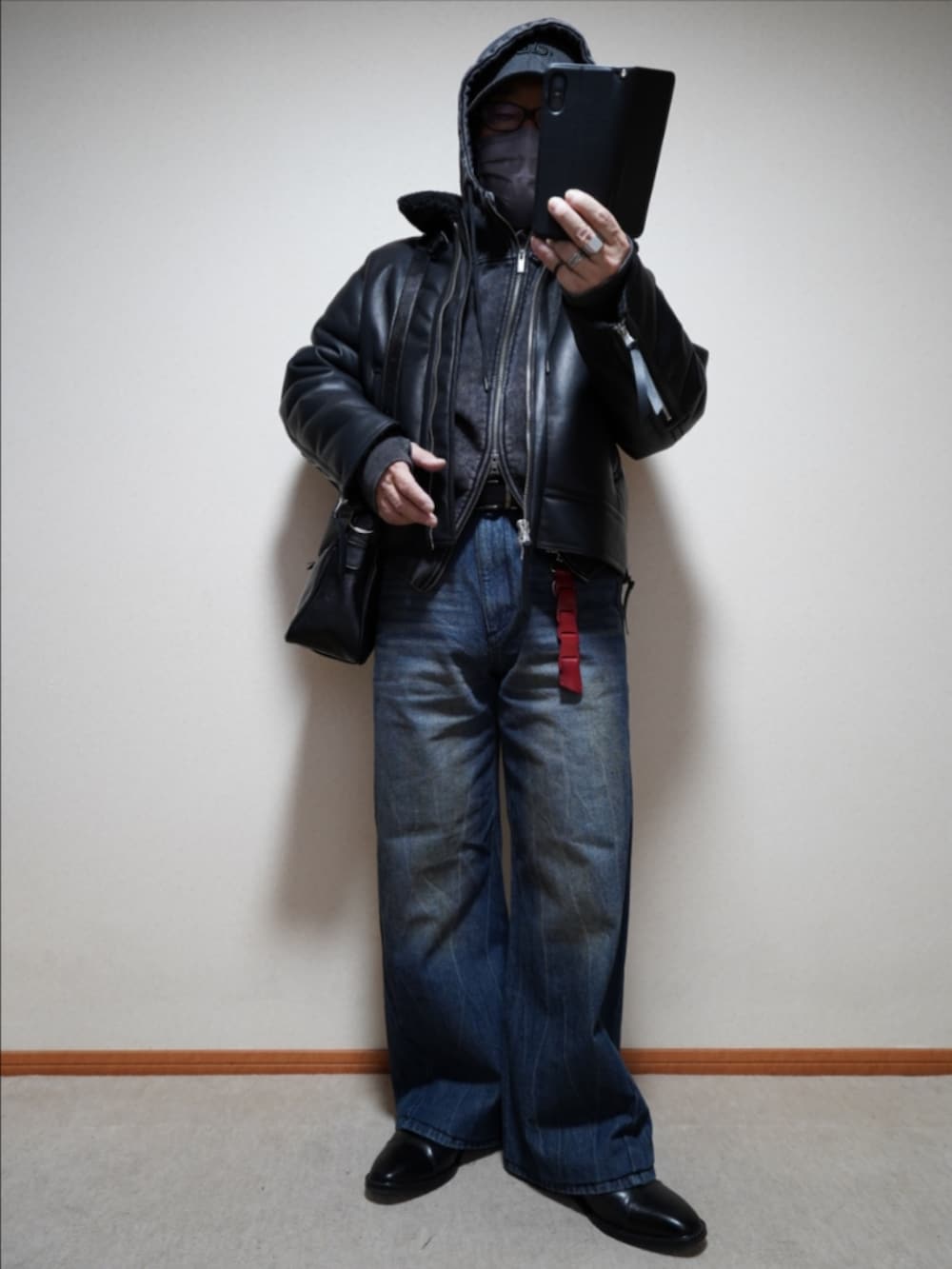 ブルー系のデニムパンツ、ブラック系のショルダーバッグ、ブラック系のパーカーを着用したメンズの冬コーディネートの2枚目の写真