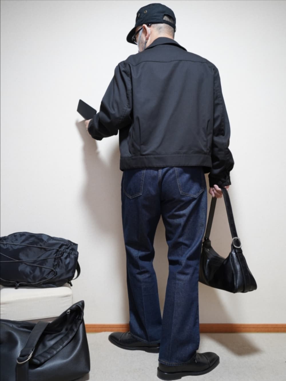 ブラック系のドレスシューズ、ブルー系のデニムパンツ、ブラック系のショルダーバッグを着用したメンズの春コーディネートの4枚目の写真