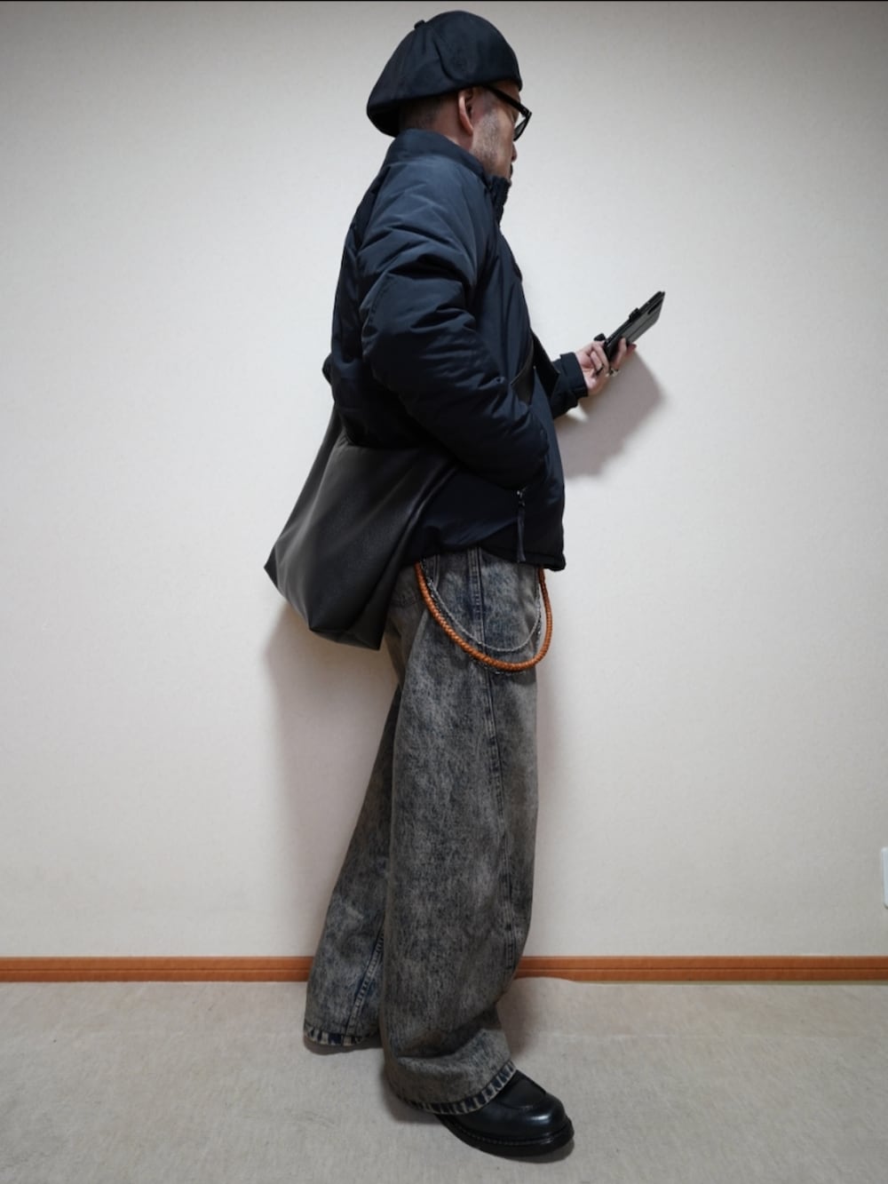 ブラック系のシューズ、ブルー系のデニムパンツ、ブラック系のダウンジャケット/コートを着用したメンズの秋コーディネートの4枚目の写真