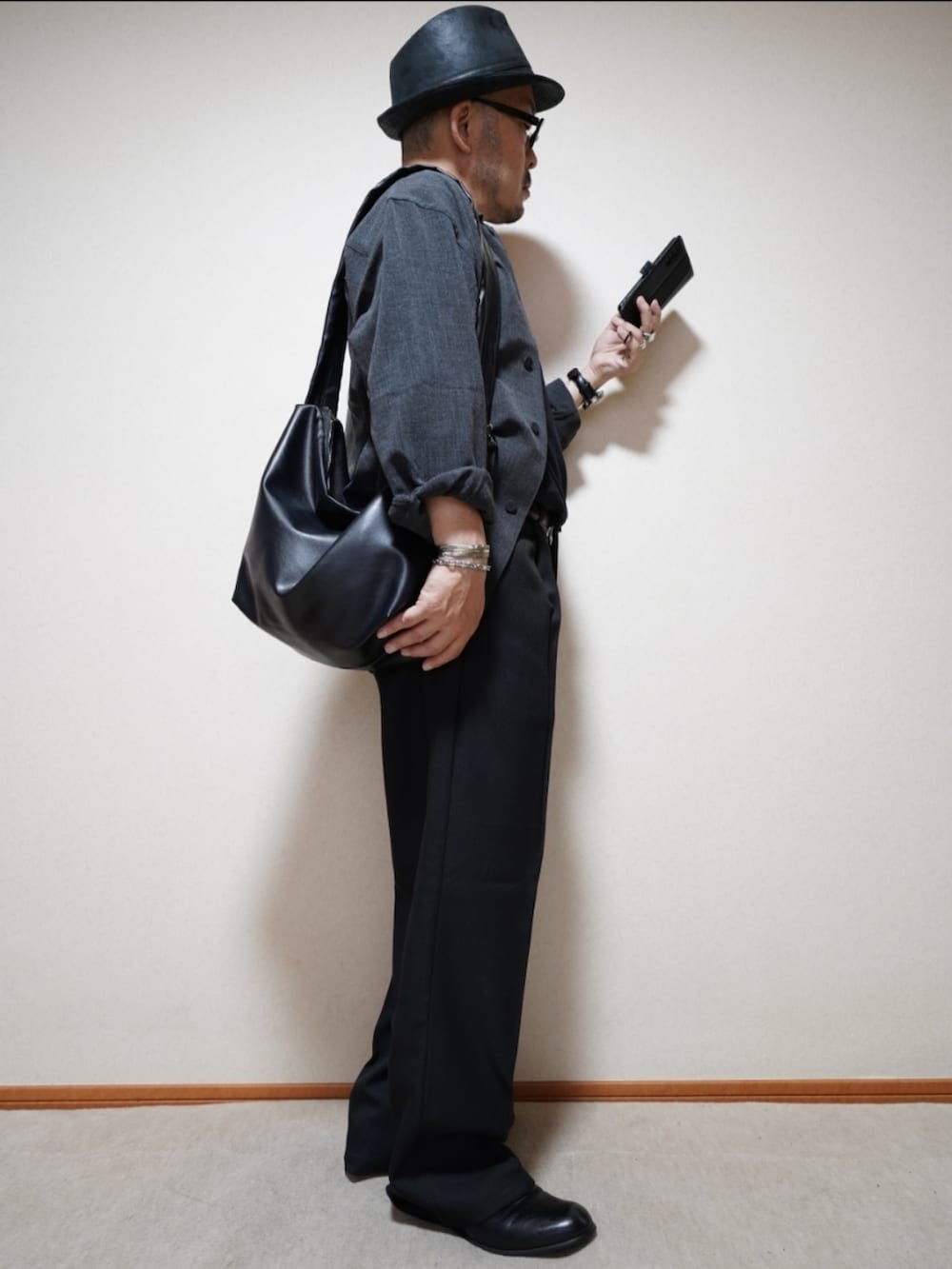 ブラック系のスリッポン、ブラック系のパンツ、ブラック系のショルダーバッグを着用したメンズの秋コーディネートの5枚目の写真