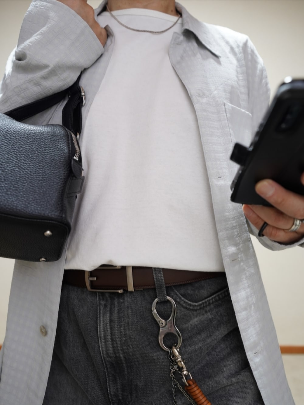 ブラック系のシューズ、グレー系のデニムパンツ、ブラック系のショルダーバッグを着用したメンズの春コーディネートの3枚目の写真