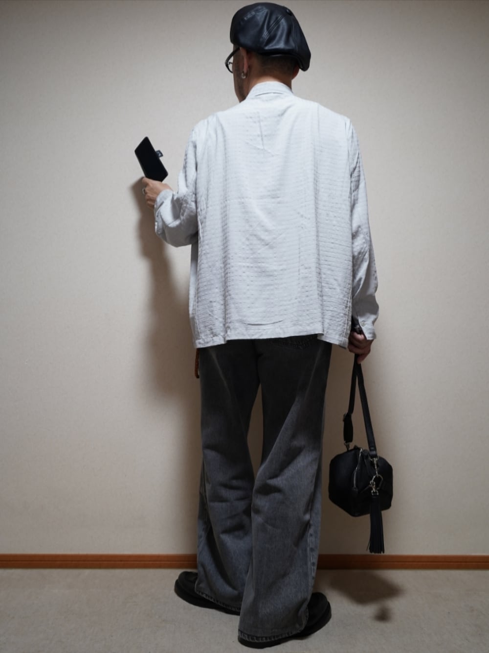 ブラック系のシューズ、グレー系のデニムパンツ、ブラック系のショルダーバッグを着用したメンズの春コーディネートの4枚目の写真