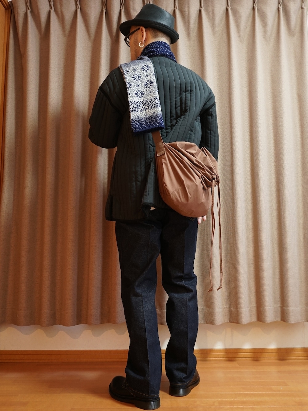 ブラック系のシューズ、ブルー系のデニムパンツ、ブラック系のミリタリージャケットを着用したメンズの秋コーディネートの2枚目の写真