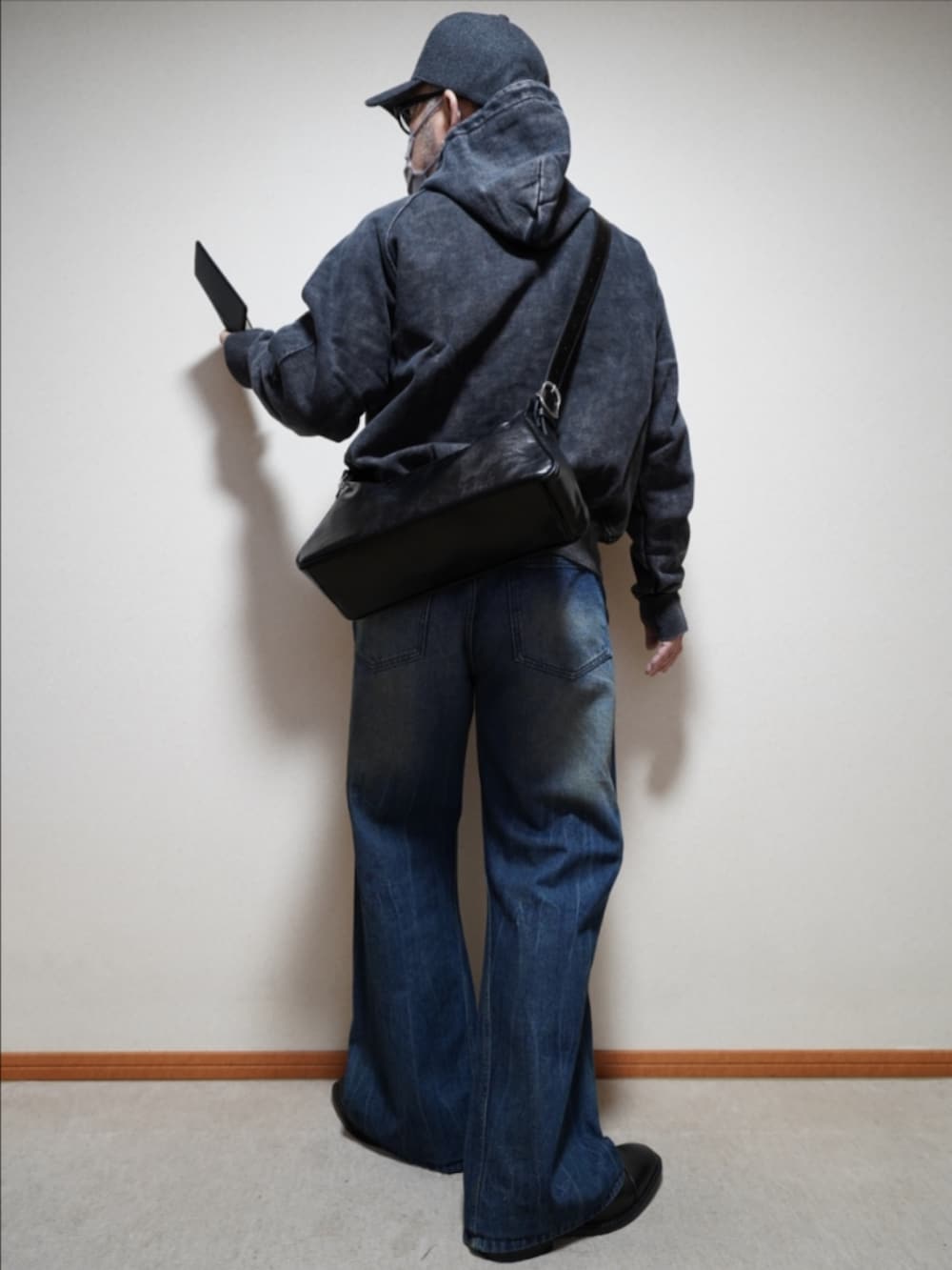 ブルー系のデニムパンツ、ブラック系のパーカー、ブラック系のショルダーバッグを着用したメンズの冬コーディネートの4枚目の写真