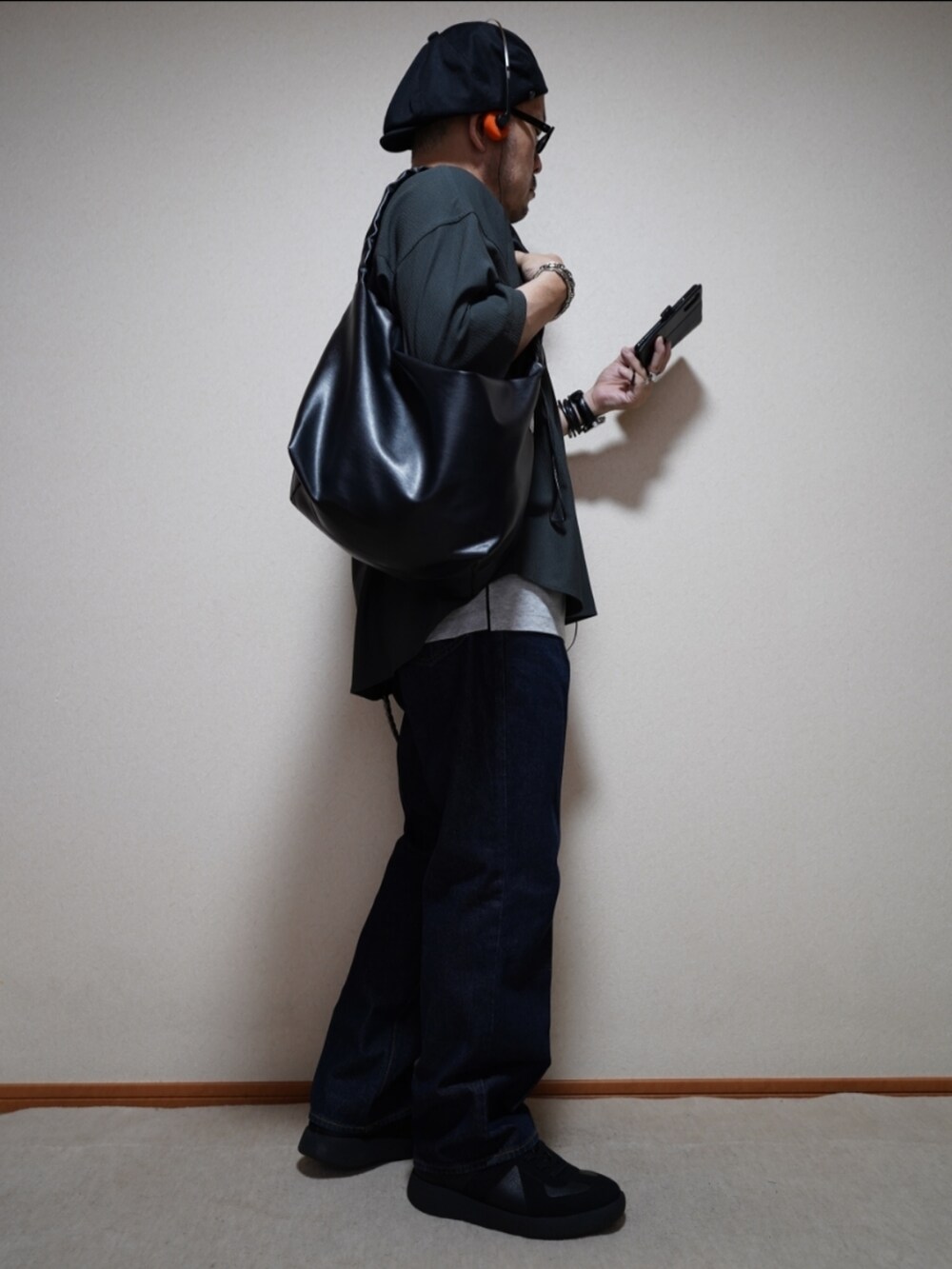 ブラック系のスニーカー、ブルー系のデニムパンツ、グレー系のタンクトップを着用したメンズの夏コーディネートの4枚目の写真