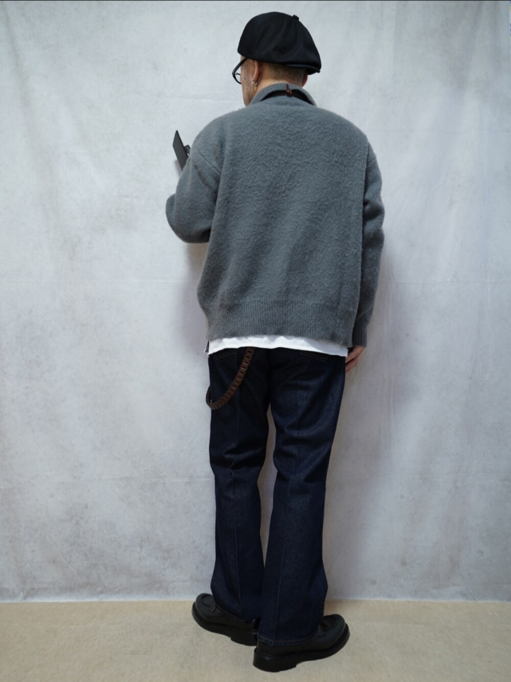ブラック系のシューズ、ブルー系のデニムパンツ、グレー系のニット/セーターを着用したメンズの春コーディネートの3枚目の写真