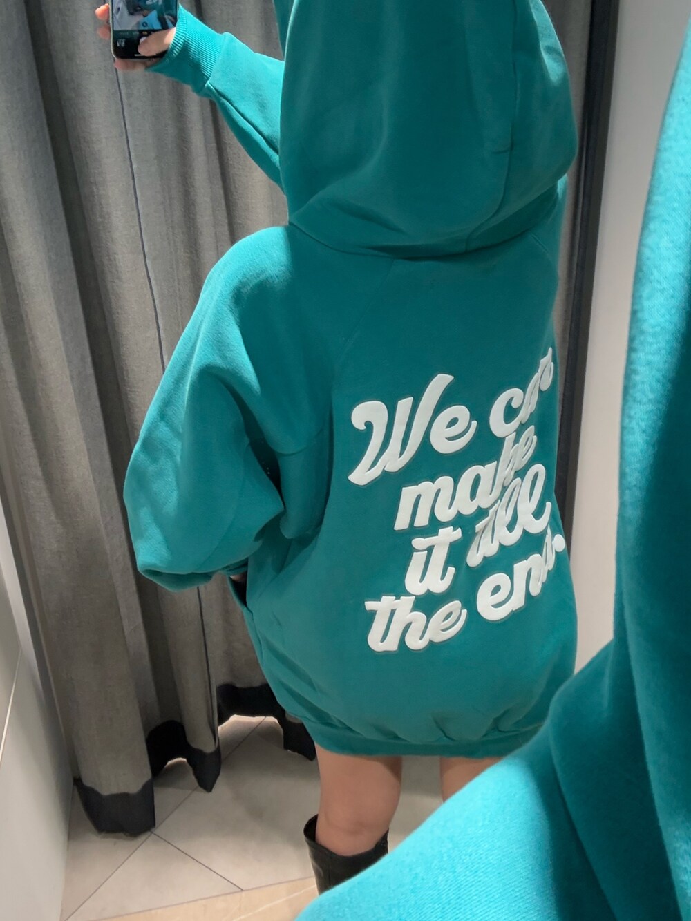 グリーン系のワンピース、ブラック系のブーツを着用したレディースの冬コーディネートの2枚目の写真