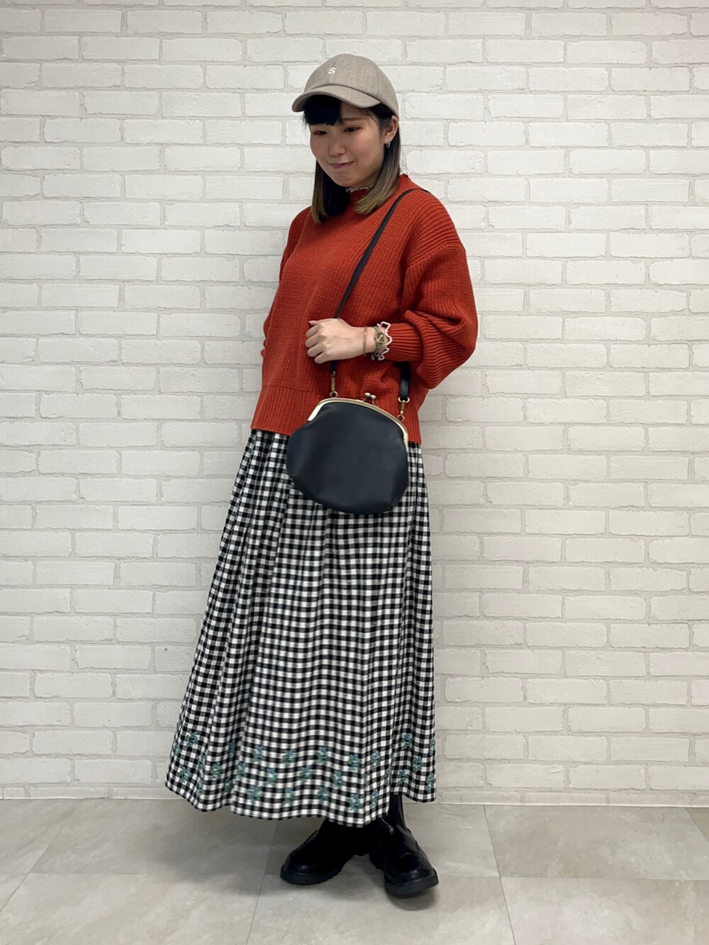レッド系のニット/セーター、ブラック系のスカート、ブラック系のブーツを着用したレディースの秋コーディネートの2枚目の写真