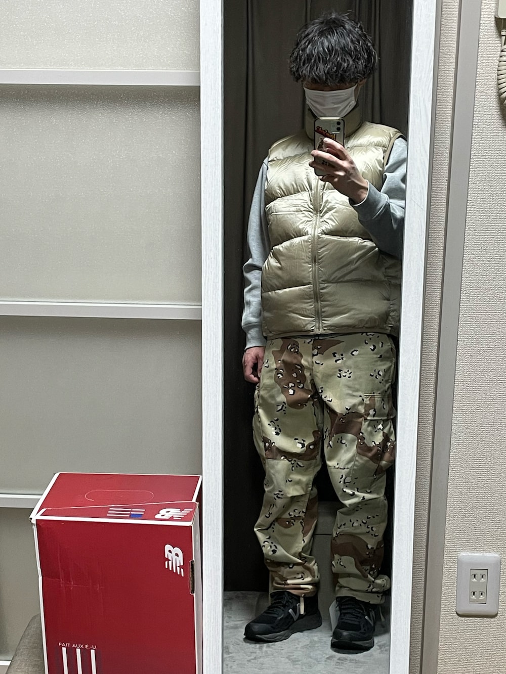 ゴールド系のダウンベスト、ベージュ系のカーゴパンツ、ブラック系のスニーカーを着用したメンズの冬コーディネートの2枚目の写真