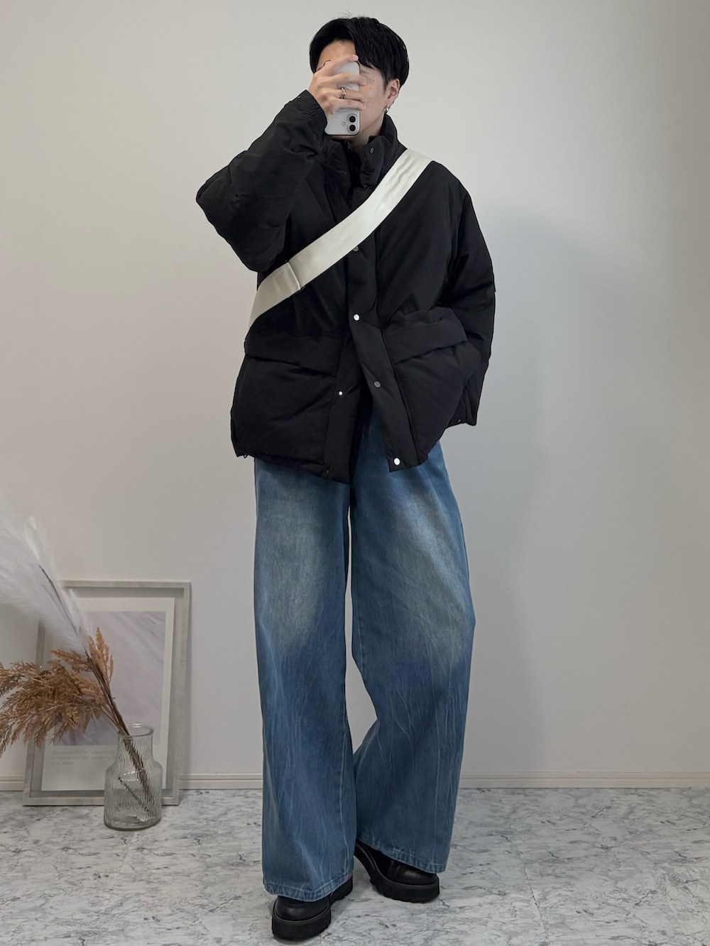 ブラック系のダウンジャケット/コート、ベージュ系のショルダーバッグ、ブルー系のデニムパンツを着用したメンズの冬コーディネートの2枚目の写真