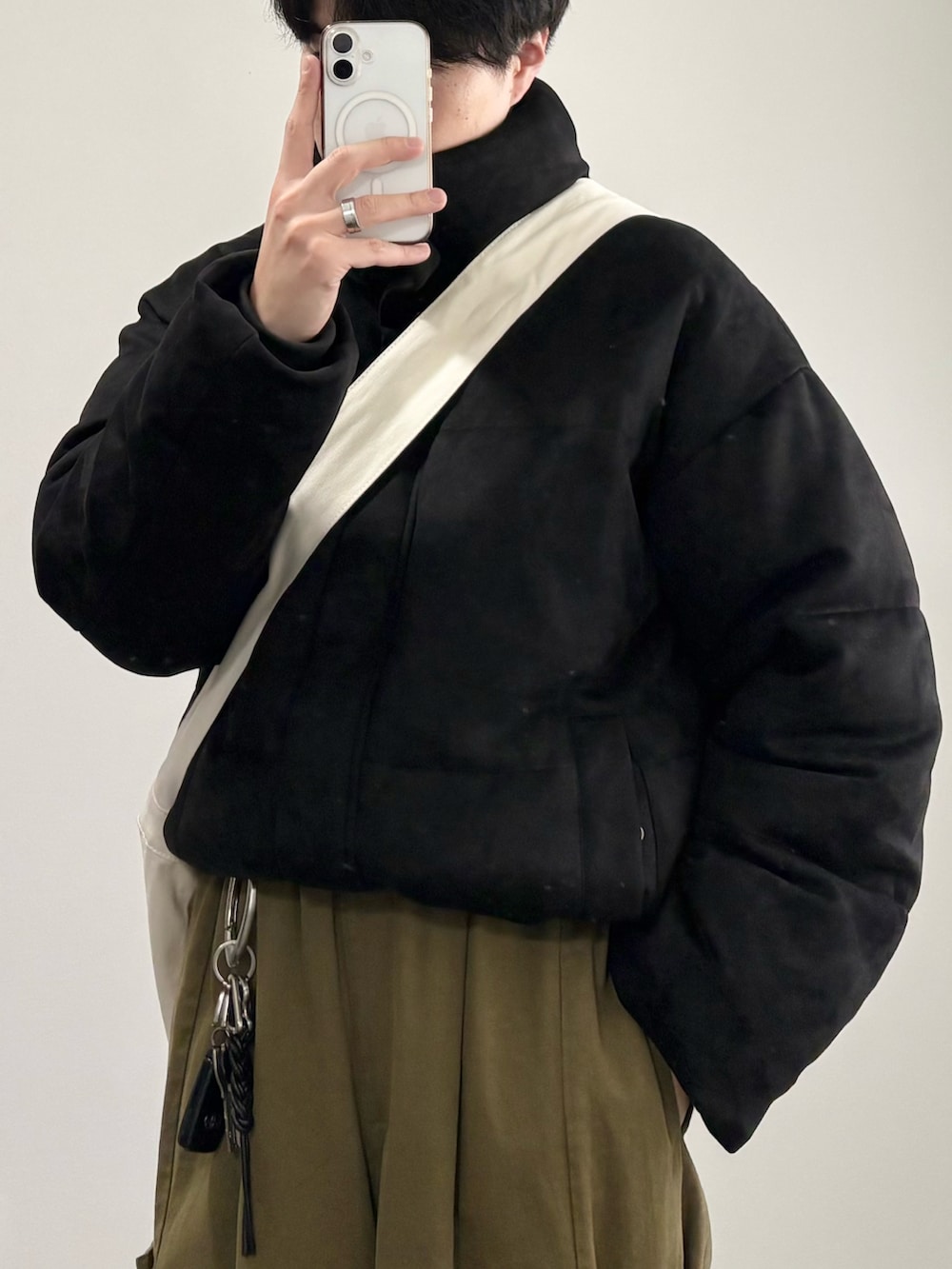 ベージュ系のショルダーバッグ、ブラック系のダウンジャケット/コート、グリーン系のカーゴパンツを着用したメンズの冬コーディネートの3枚目の写真