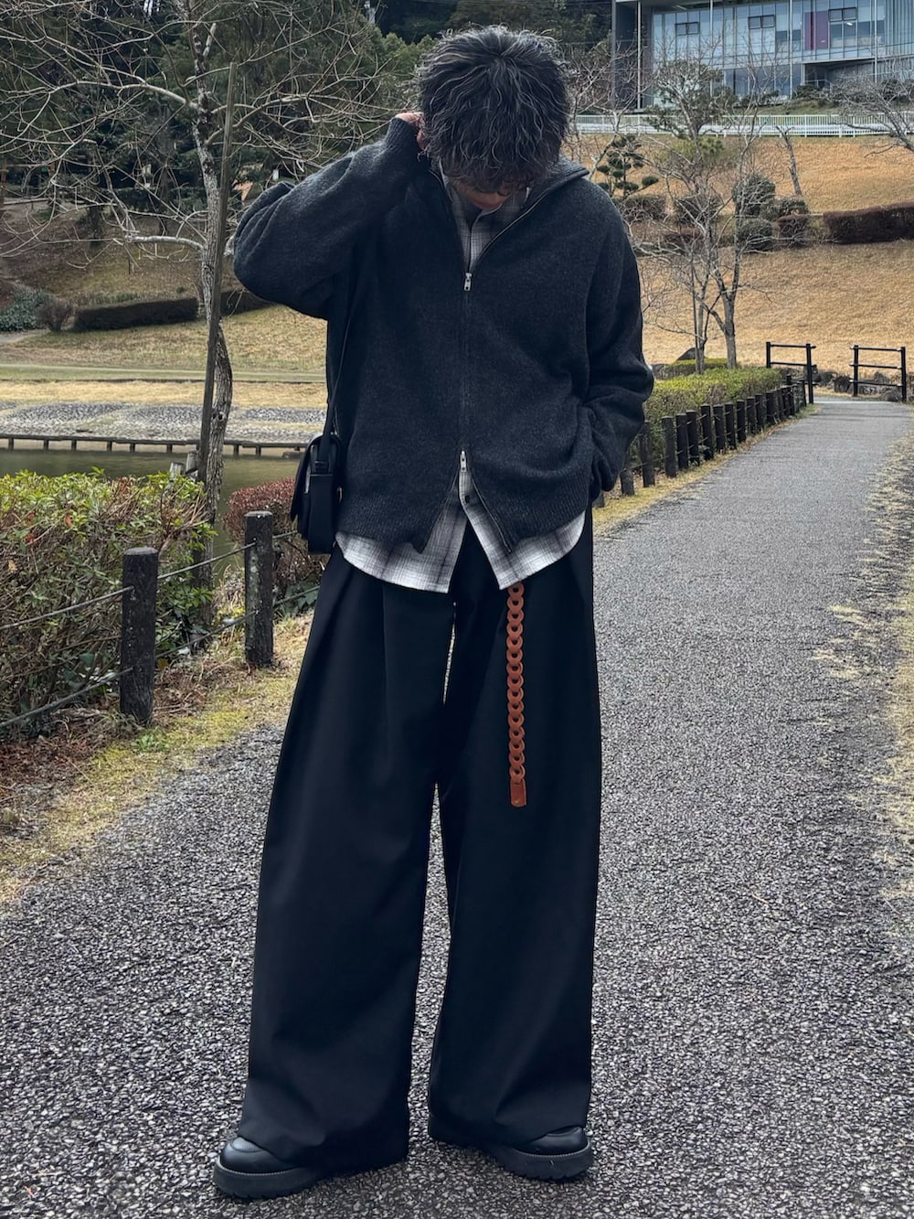 グレー系のニット/セーター、ブラック系のショルダーバッグ、ブラック系のドレスシューズを着用したメンズの春コーディネートの2枚目の写真