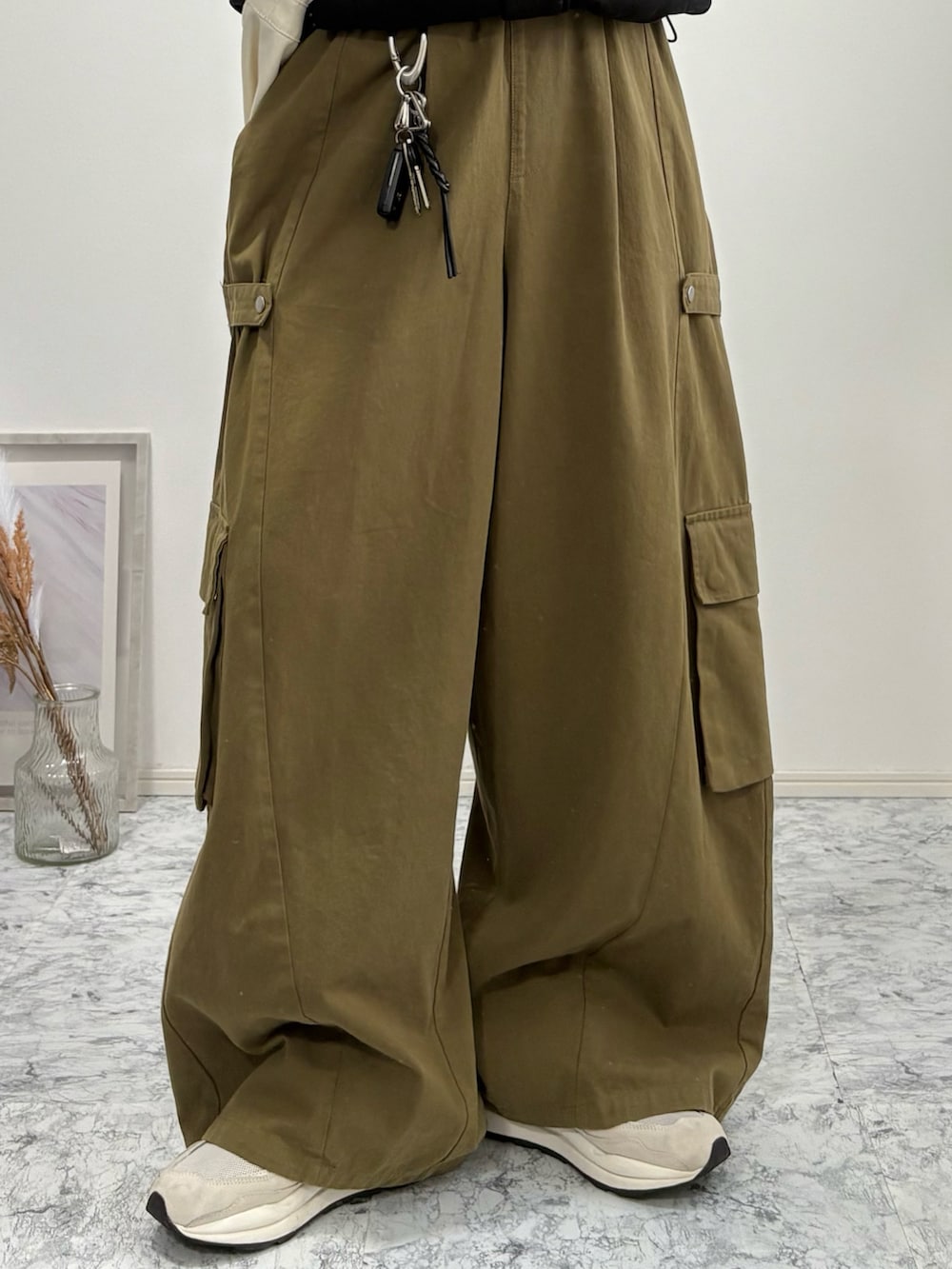 ベージュ系のショルダーバッグ、ブラック系のダウンジャケット/コート、グリーン系のカーゴパンツを着用したメンズの冬コーディネートの4枚目の写真