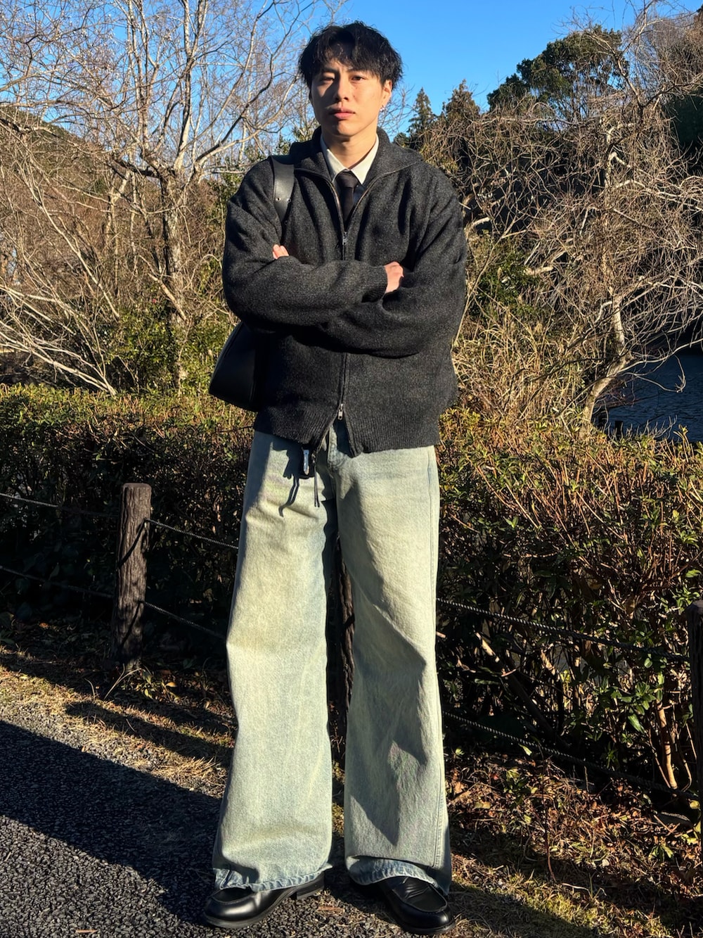 ブラック系のローファー、グレー系のニット/セーター、ブルー系のデニムパンツを着用したメンズの春コーディネートの2枚目の写真