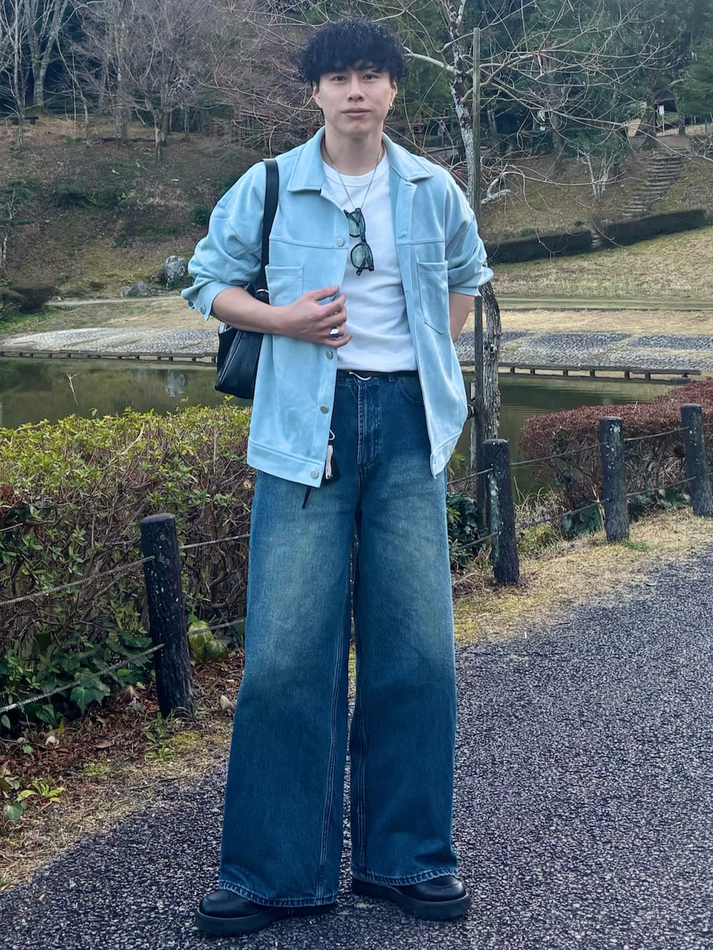 ブルー系のデニムパンツ、ブラック系のショルダーバッグ、ブラック系のドレスシューズを着用したメンズの春コーディネートの3枚目の写真