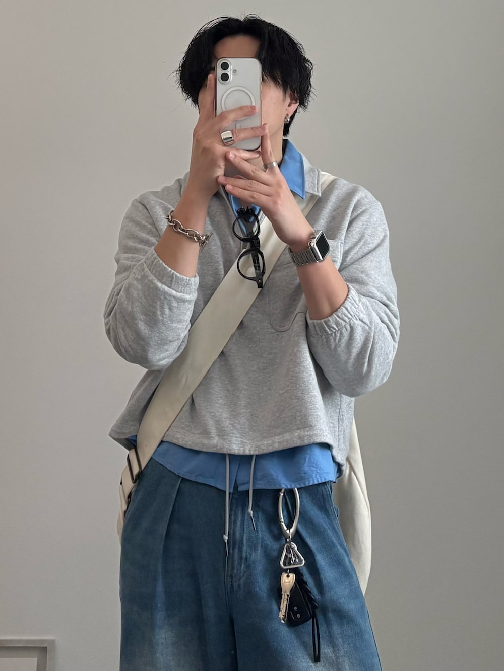 ベージュ系のショルダーバッグ、ブルー系のデニムパンツ、ベージュ系のスニーカーを着用したメンズの春コーディネートの3枚目の写真