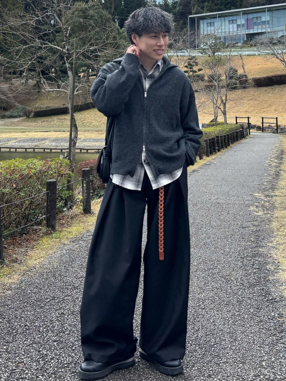 グレー系のニット/セーター、ブラック系のショルダーバッグ、ブラック系のドレスシューズを着用したメンズの春コーディネートの3枚目の写真