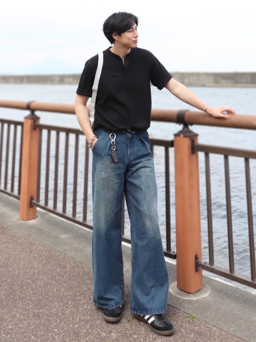 ブルー系のデニムパンツ、ブラック系のスニーカー、ブラック系のTシャツ/カットソーを着用したメンズの夏コーディネートの2枚目の写真