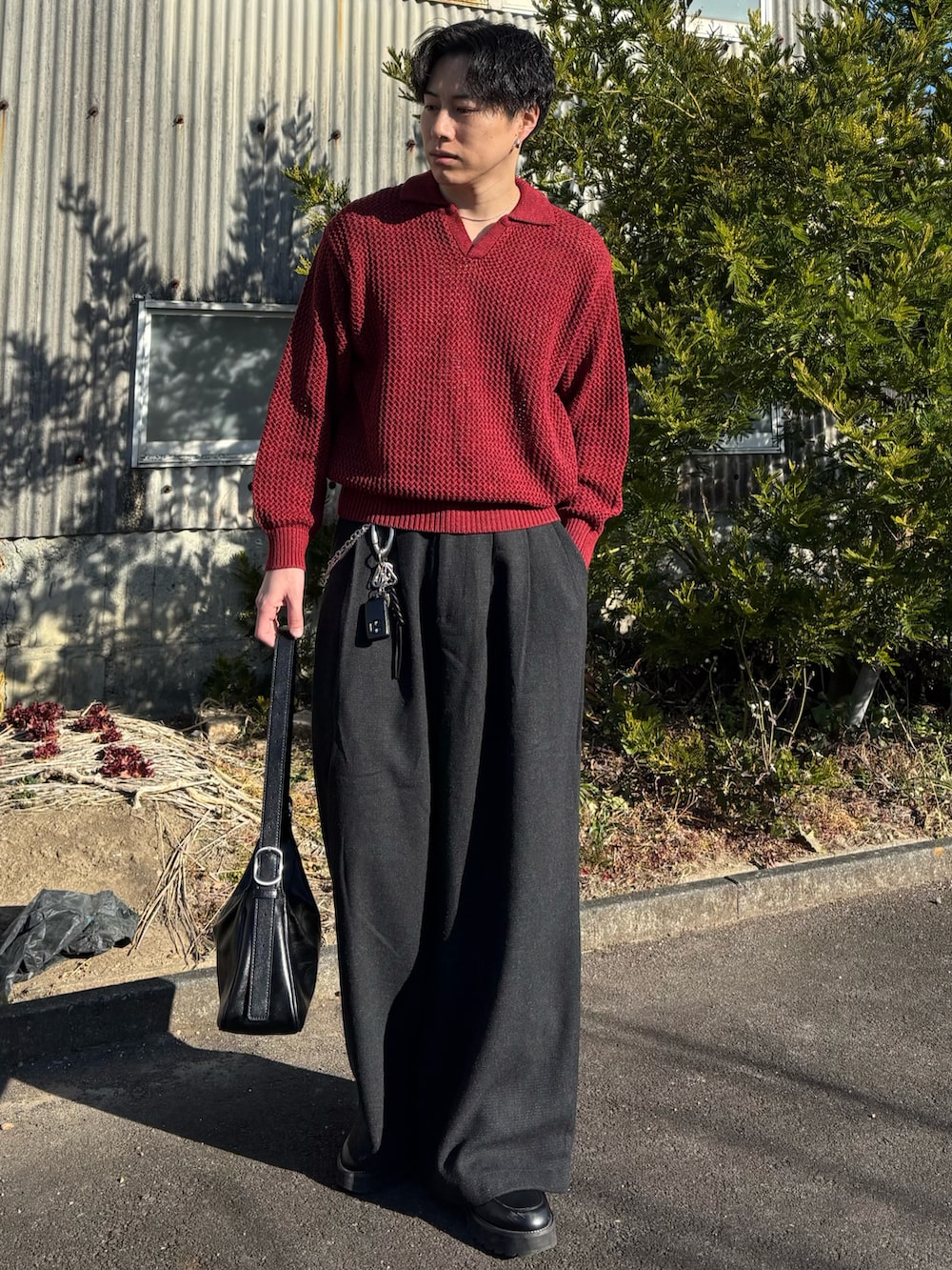 レッド系のニット/セーター、ブラック系のスウェットパンツ、ブラック系のショルダーバッグを着用したメンズの春コーディネートの2枚目の写真