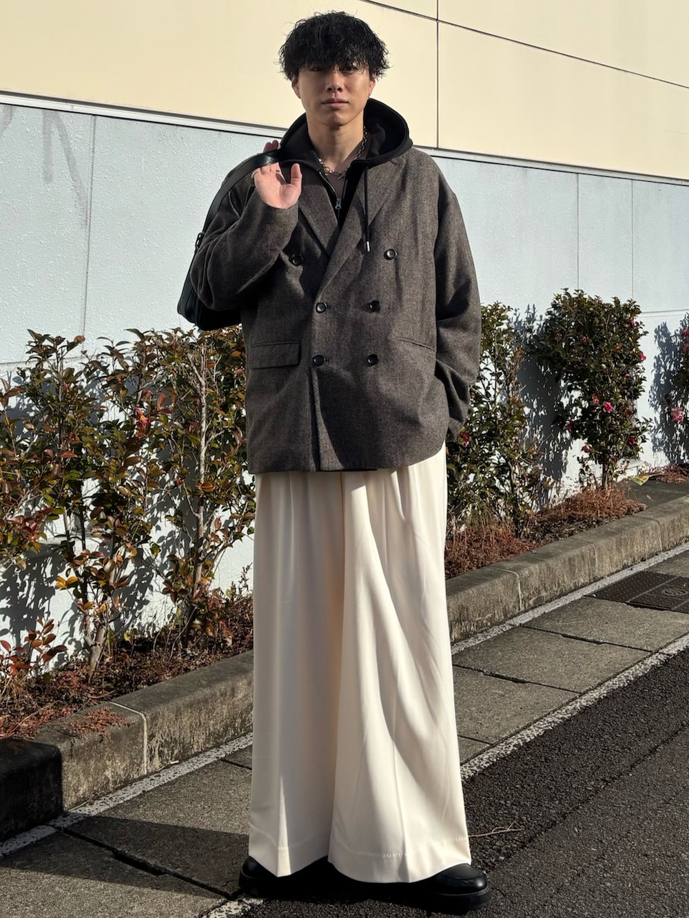 ブラック系のパーカー、グレー系のテーラードジャケット、ホワイト系のスラックスを着用したメンズの春コーディネートの3枚目の写真