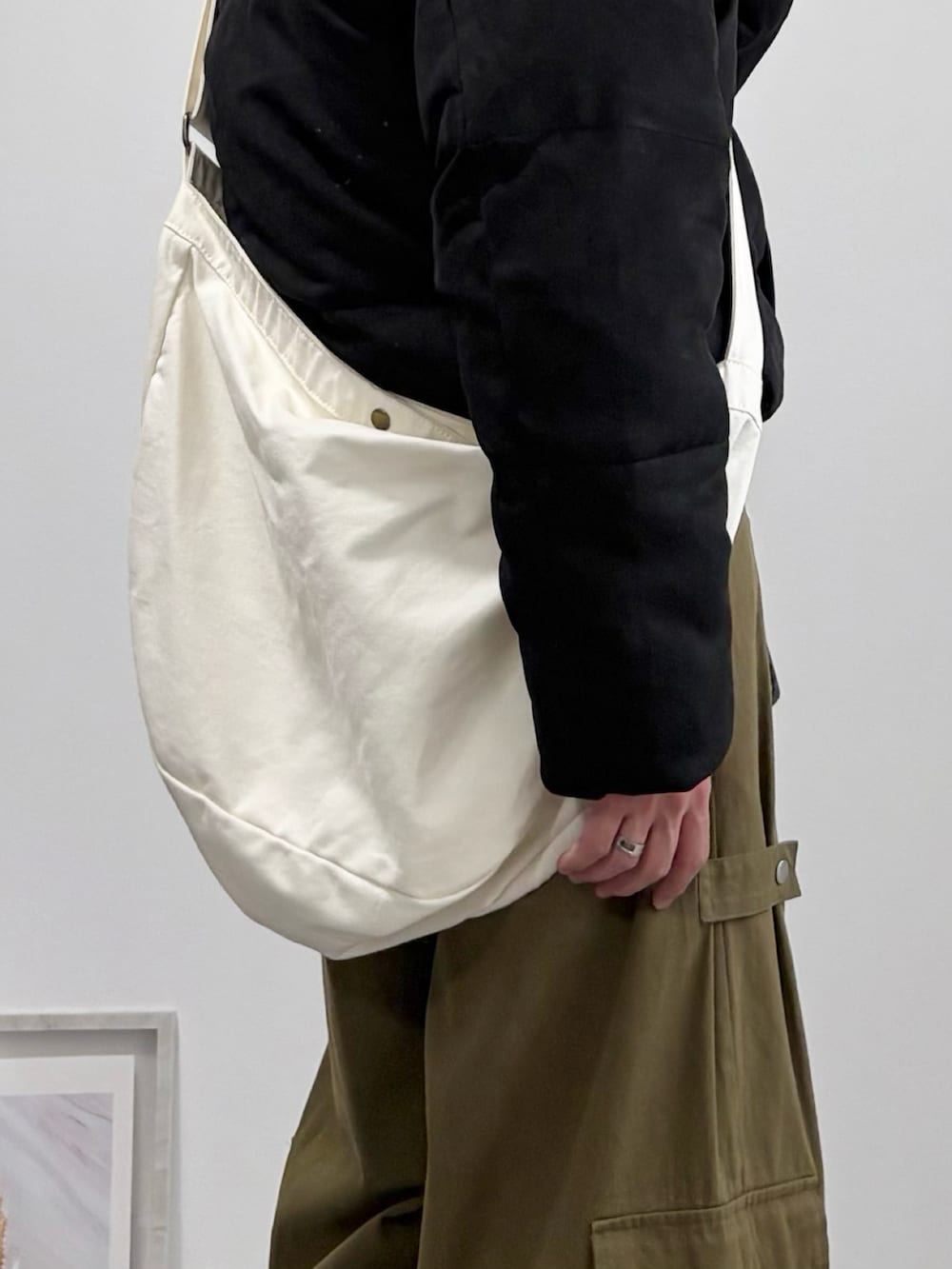 ベージュ系のショルダーバッグ、ブラック系のダウンジャケット/コート、グリーン系のカーゴパンツを着用したメンズの冬コーディネートの5枚目の写真