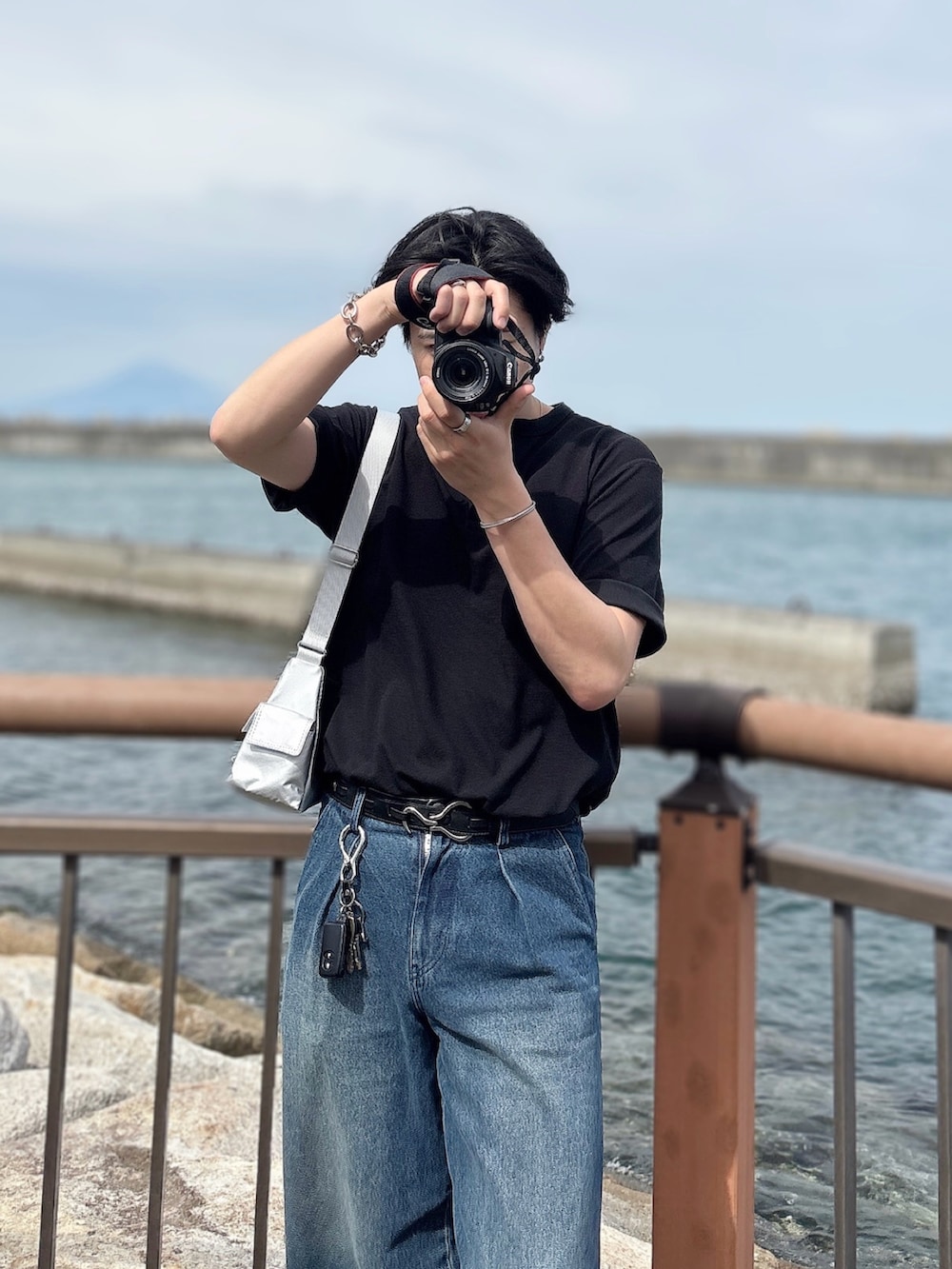 ブルー系のデニムパンツ、ブラック系のスニーカー、ブラック系のTシャツ/カットソーを着用したメンズの夏コーディネートの3枚目の写真