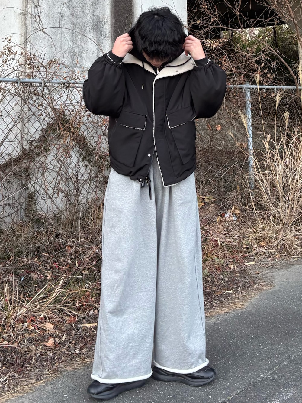 ブラック系のブルゾン、ブラック系のパーカー、グレー系のスウェットパンツを着用したメンズの春コーディネートの2枚目の写真